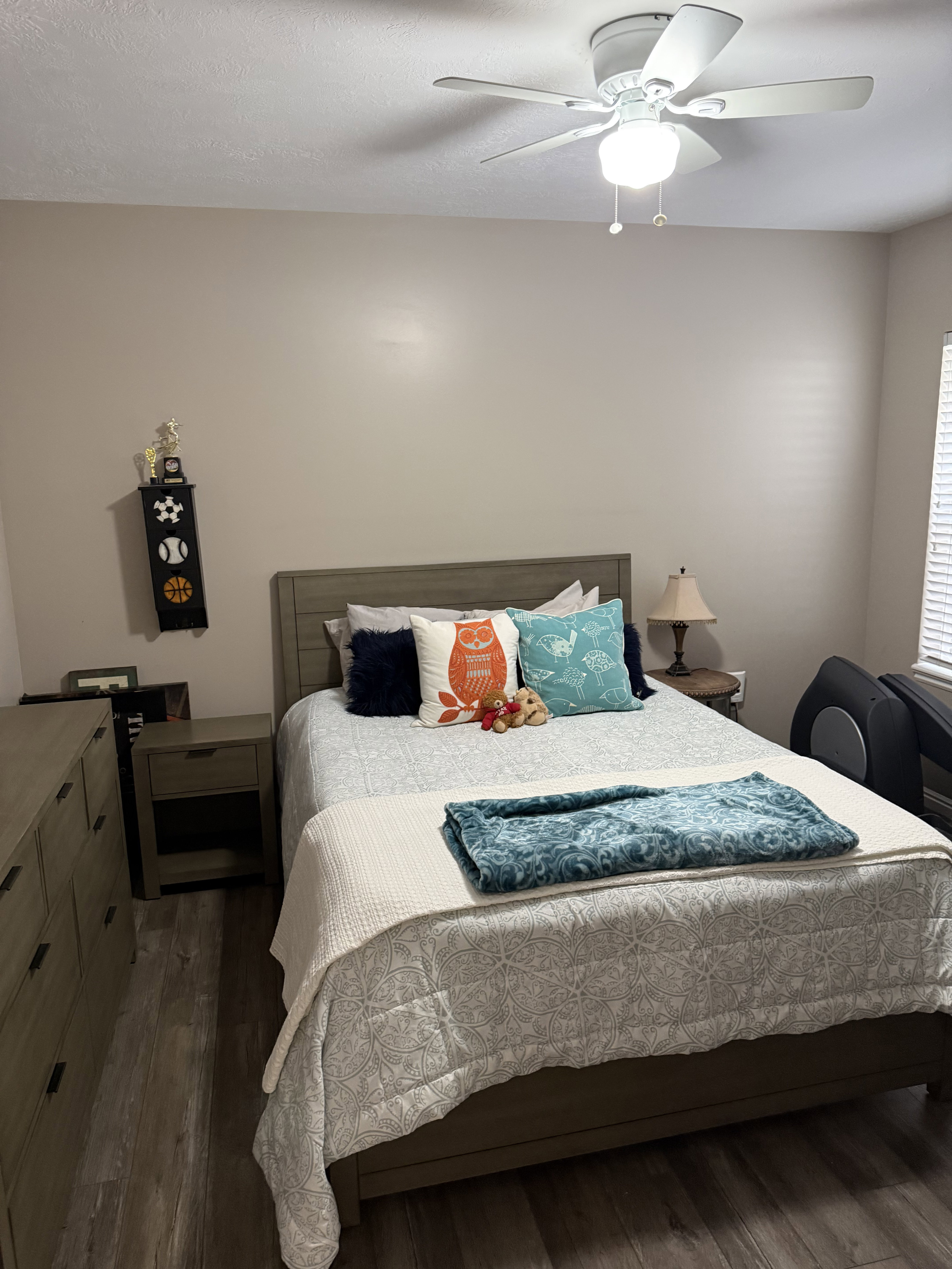 Bedroom featuring wood-finish flooring, a ceiling fan with integrated lighting, and a window with blinds