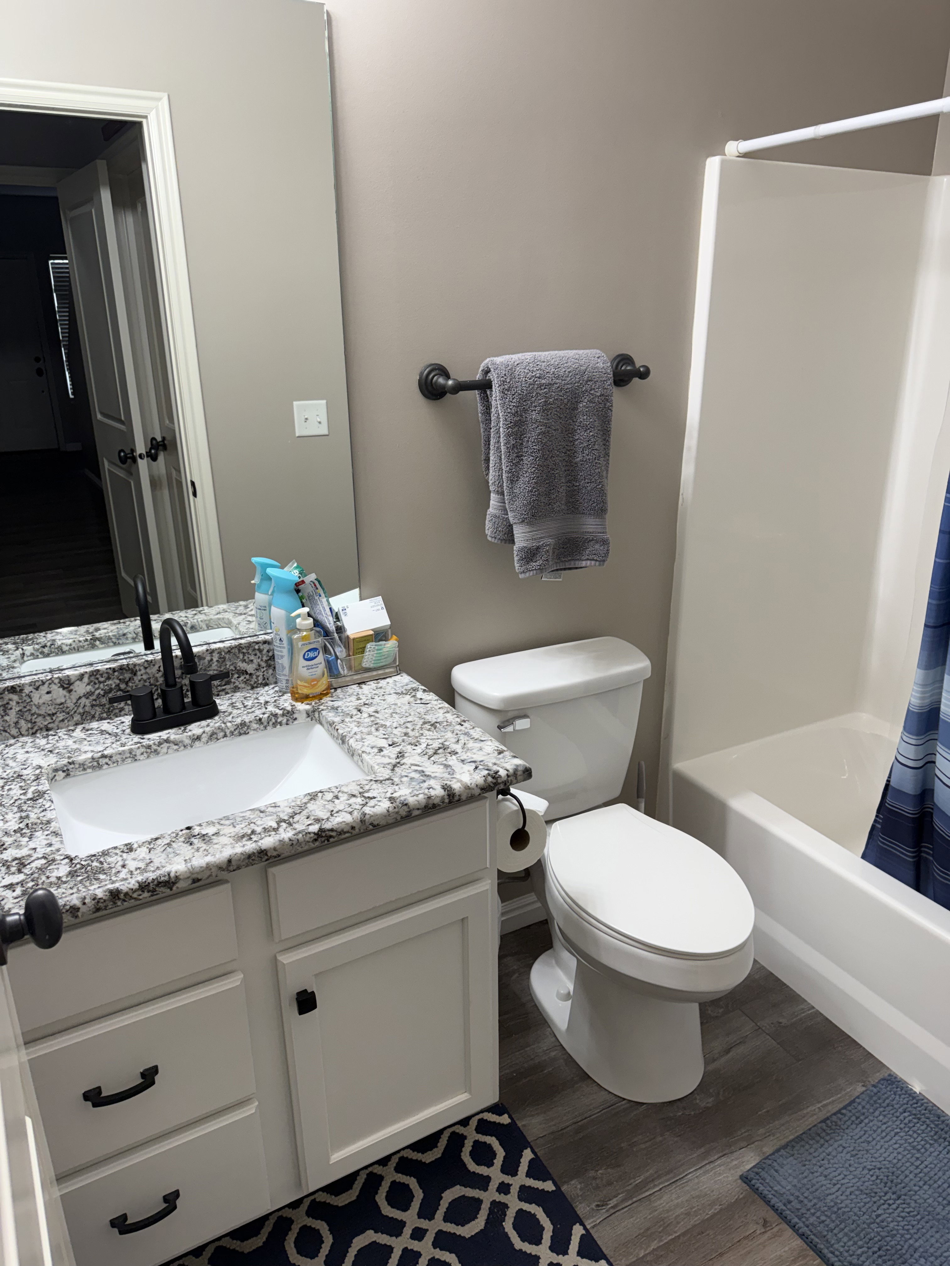 Bathroom featuring a white vanity with a speckled countertop, undermount sink, and matte black faucet