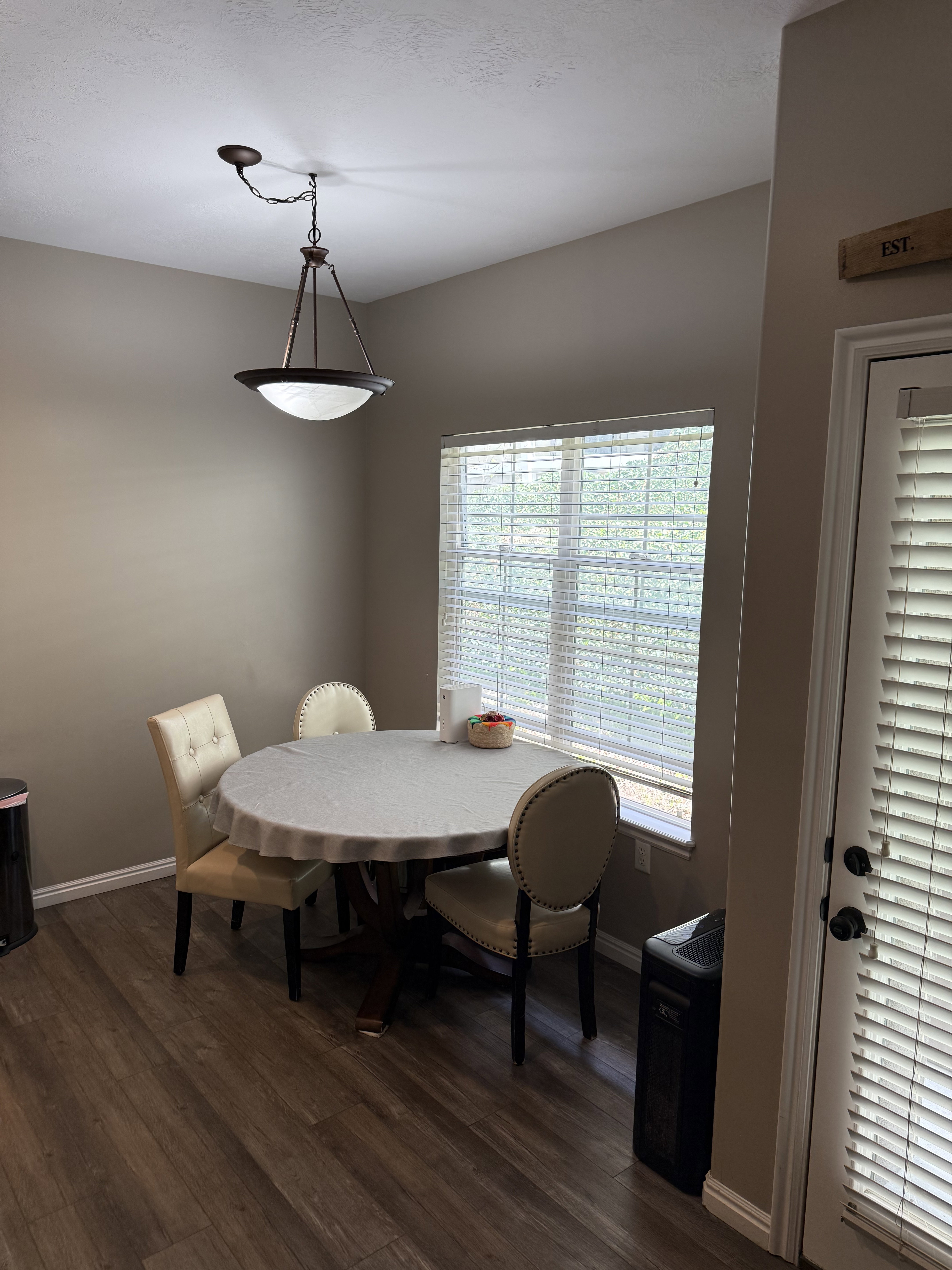 Dining area featuring wood-finish flooring, a window with blinds, and a bronze-finish ceiling light fixture