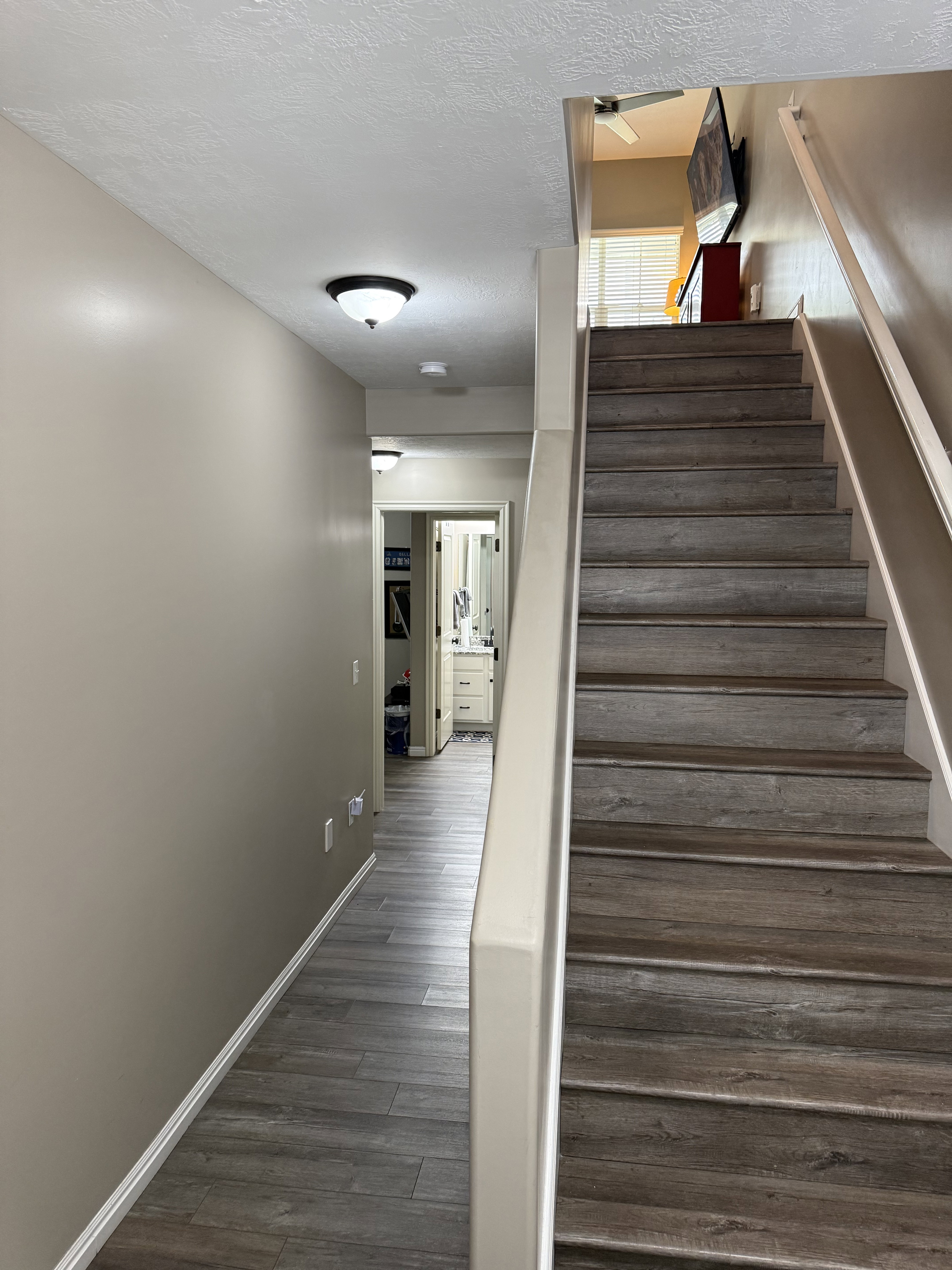 Staircase featuring wood-finish treads and risers, complemented by an adjacent hallway with wood-finish flooring