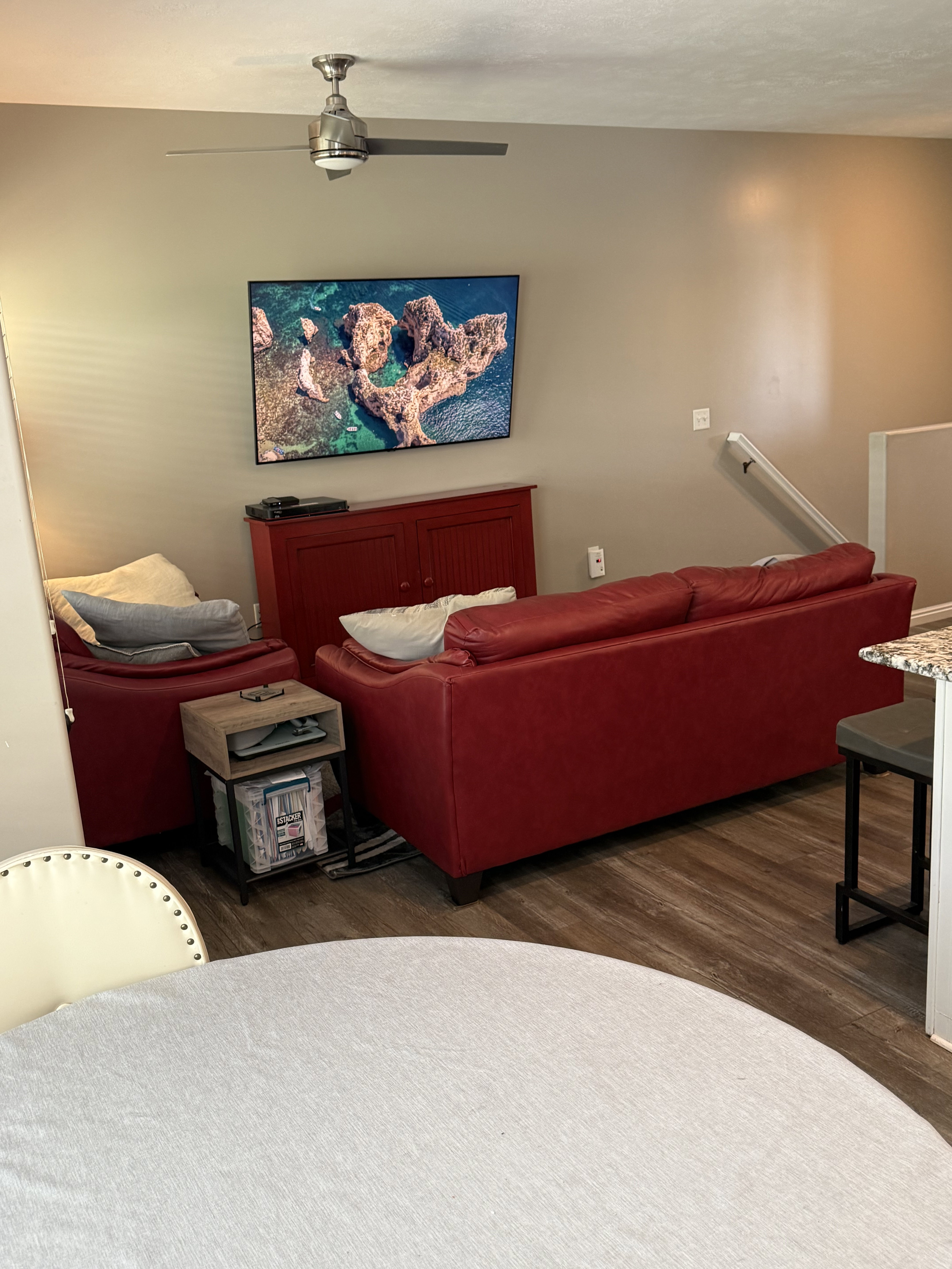 Living area featuring wood-finish flooring, a contemporary ceiling fan with integrated lighting, and a neutral wall color