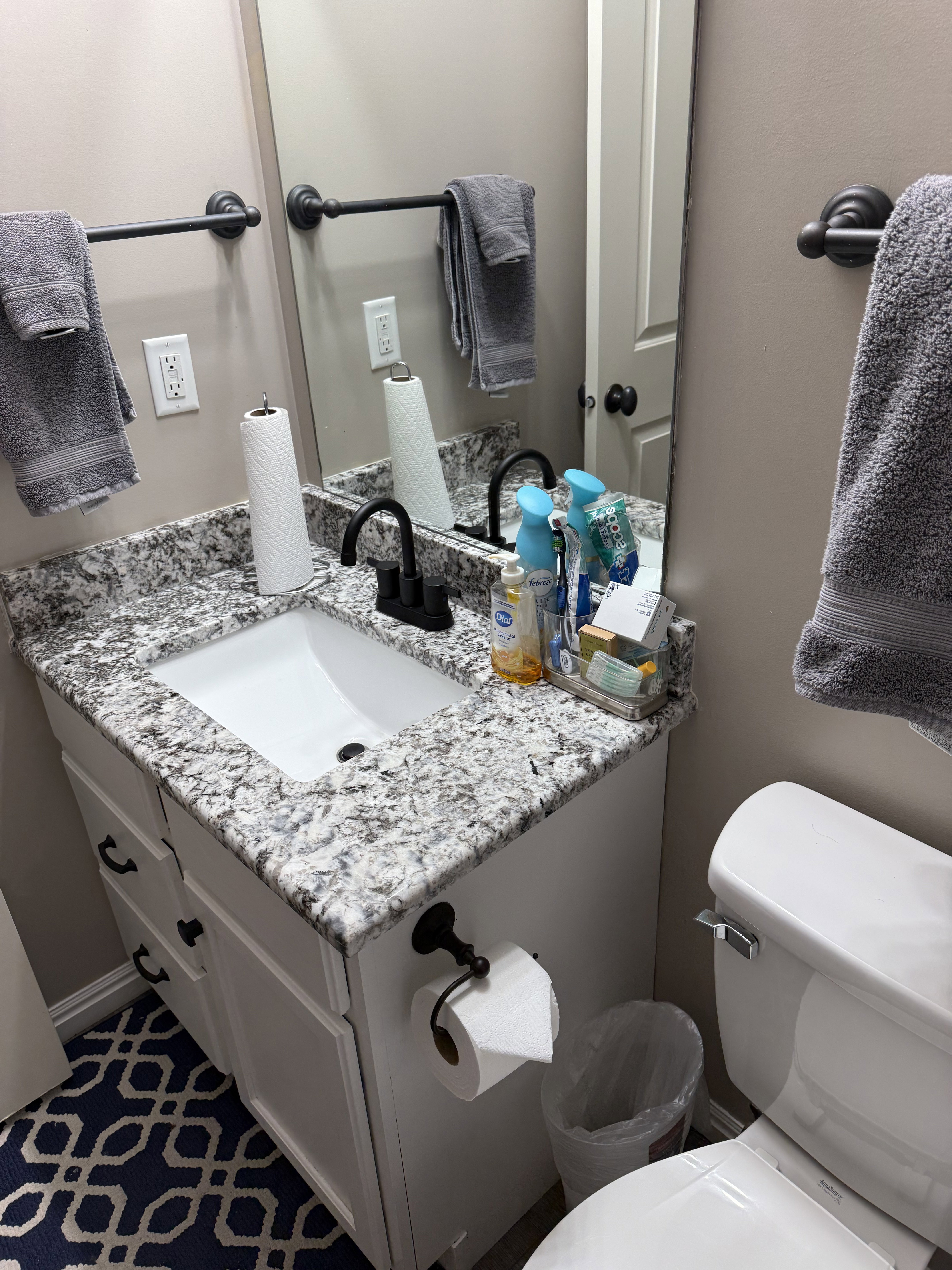 Bathroom vanity featuring a white undermount sink and a speckled countertop