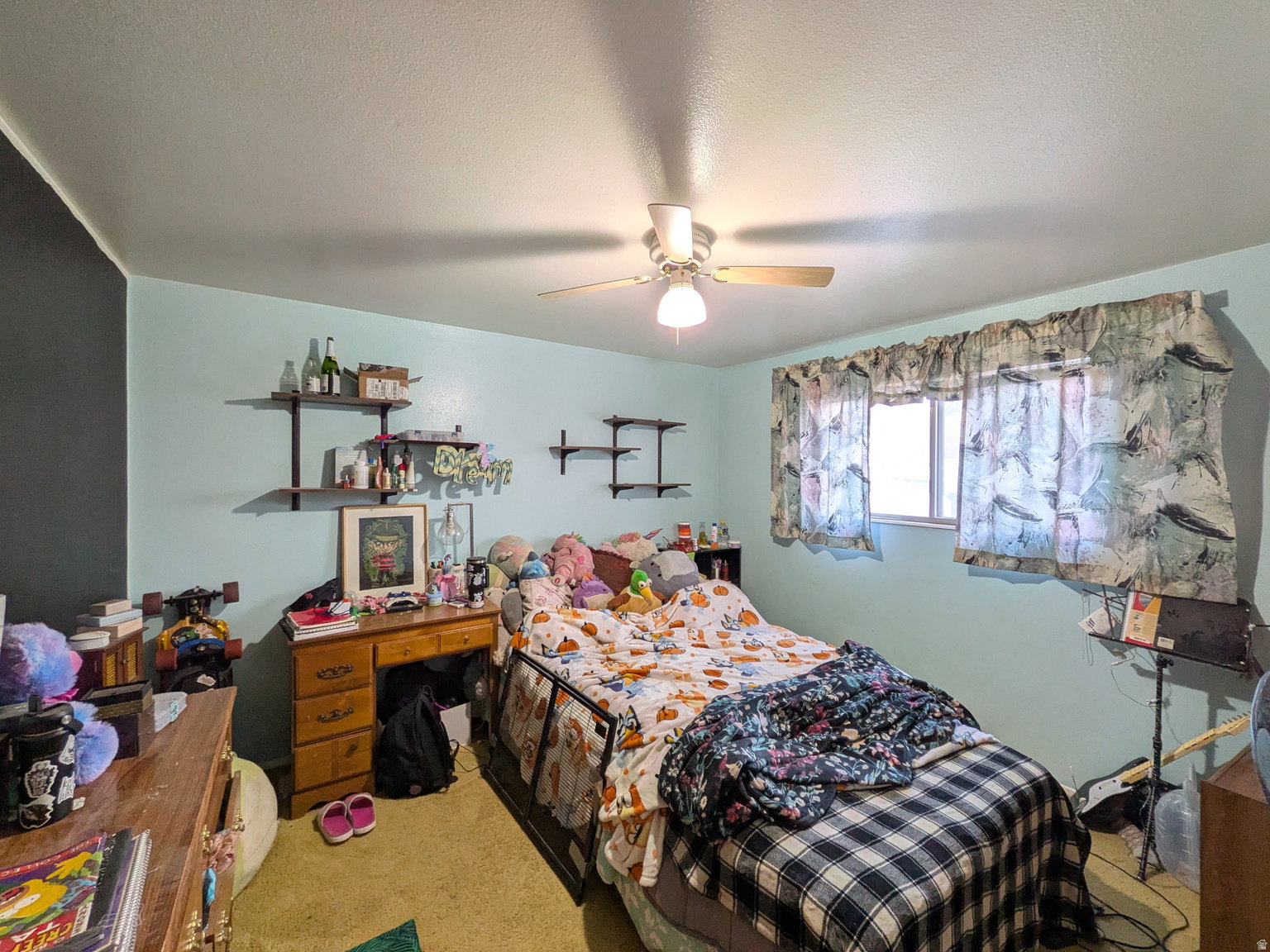 Bedroom featuring a ceiling fan with integrated lighting, a window, and wall-mounted shelving units