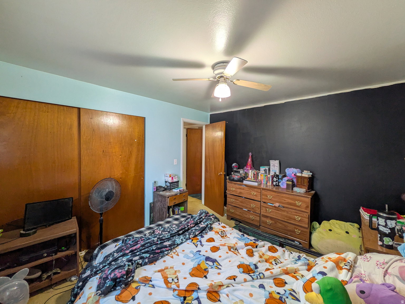 Interior room featuring a ceiling fan with integrated lighting, wood-finish bi-fold closet doors, and a wood-finish interior door