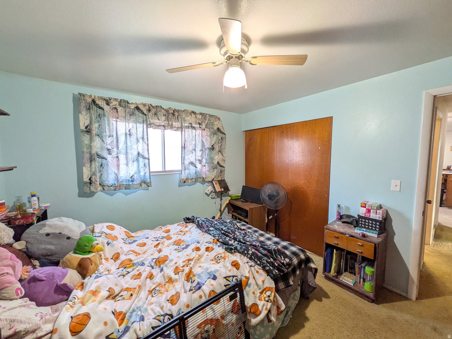 Interior room featuring a single window with a light-filtering covering, a ceiling fan with integrated lighting, and wood-finish closet doors