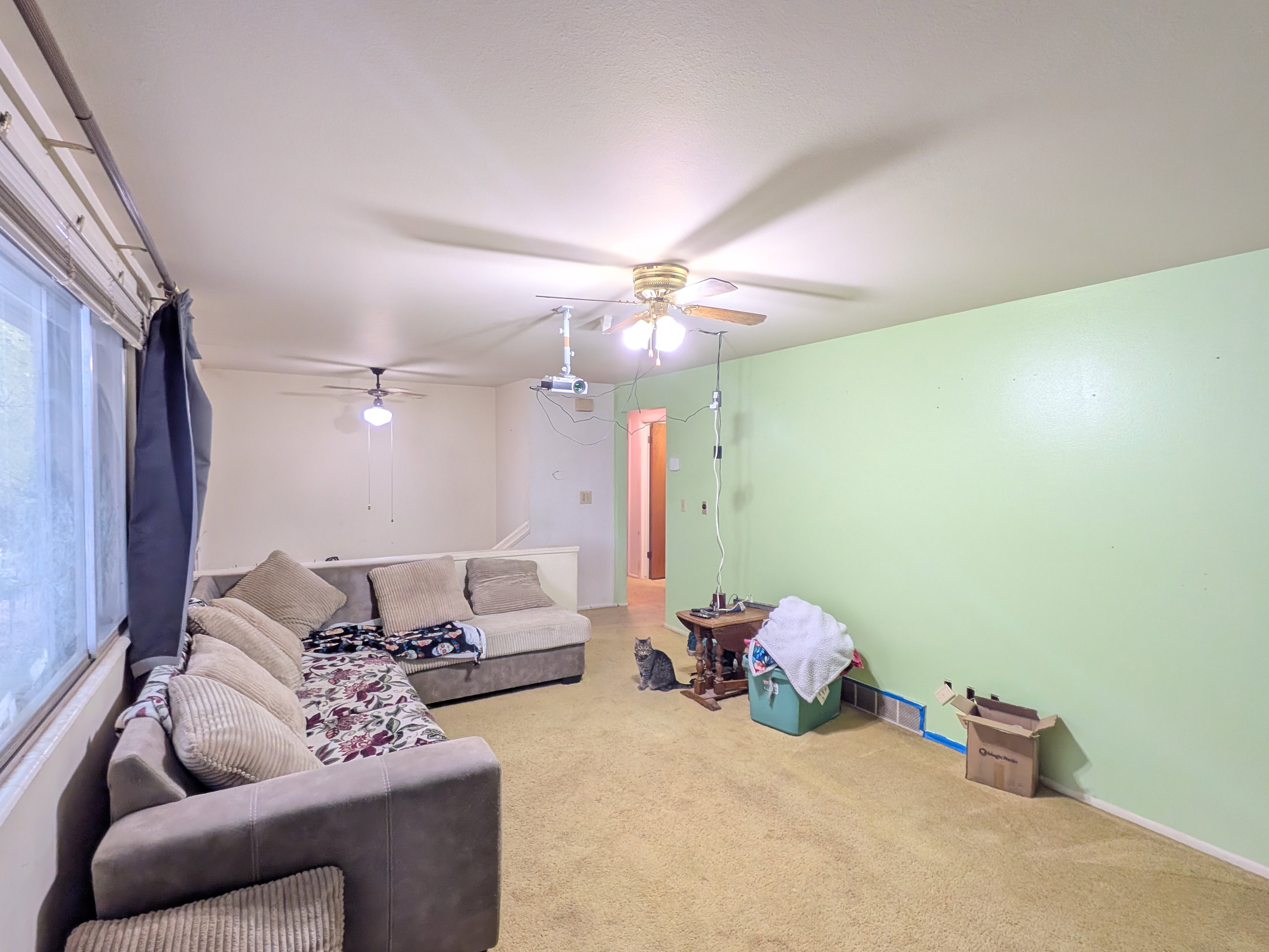 Bright interior space featuring a large window, light-colored walls, and a ceiling fan
