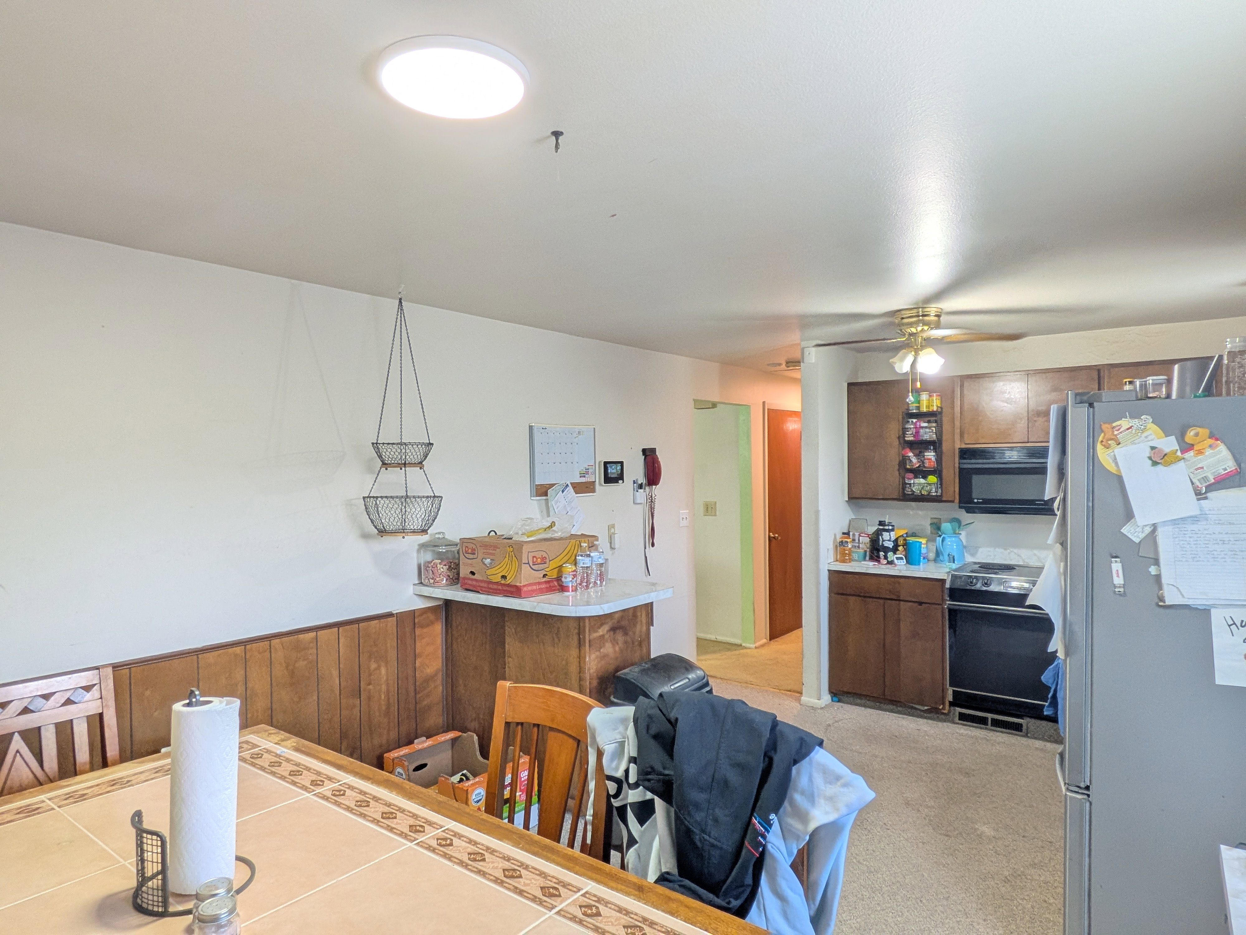 Kitchen featuring brown wood cabinetry, black appliances, and a ceiling fan with integrated lighting
