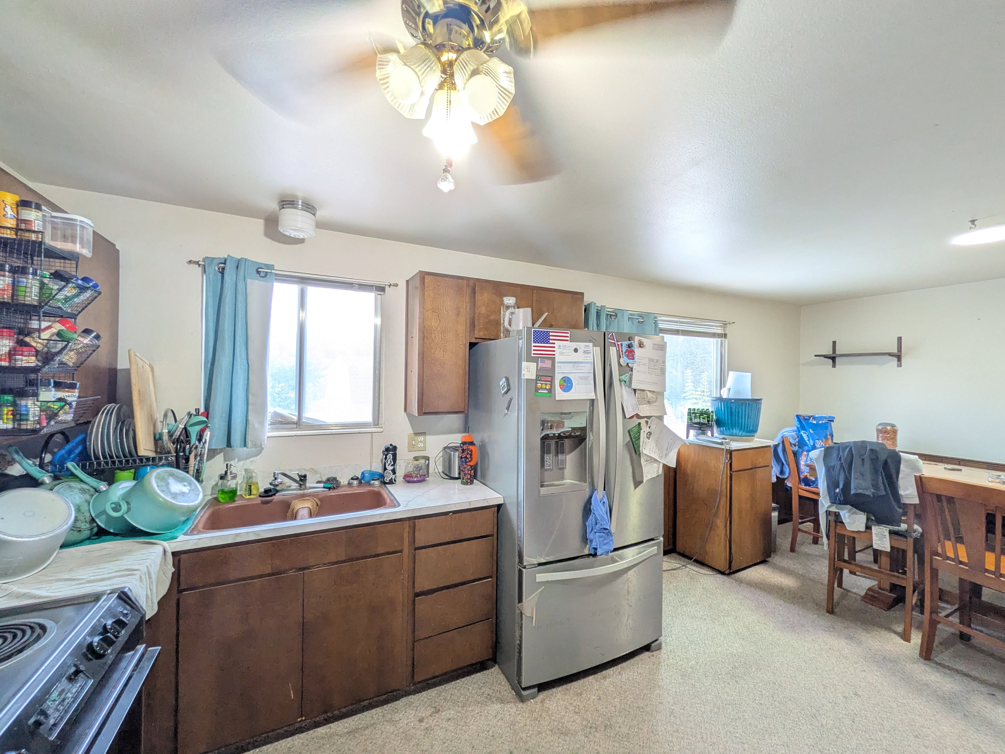 Kitchen featuring a stainless steel French door refrigerator, wood-finish cabinetry, a bronze-toned sink, and a ceiling fan