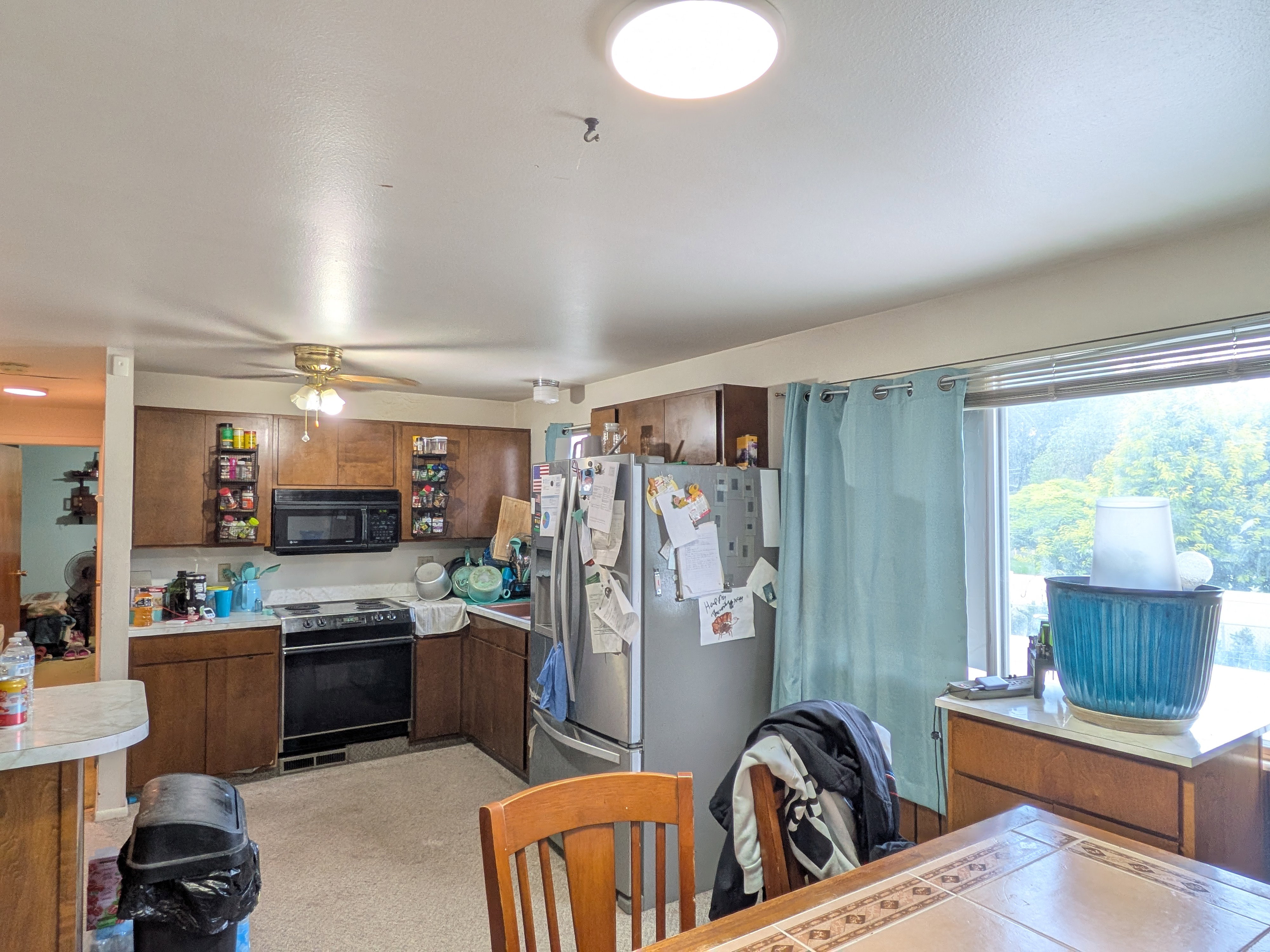 Kitchen featuring wood cabinetry, a stainless steel refrigerator, and a black electric range with a built-in microwave