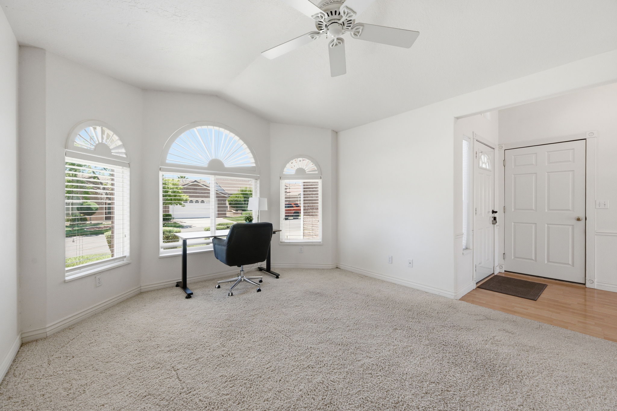 Bay window area featuring three arched windows with horizontal blinds, providing abundant natural light