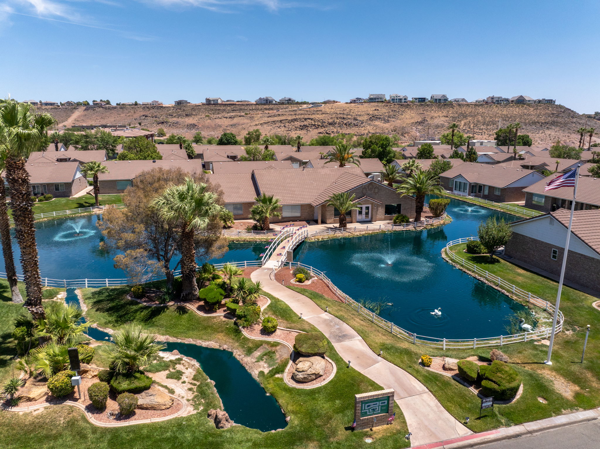 Community setting featuring a tranquil pond with multiple fountains, surrounded by mature palm trees and manicured landscaping