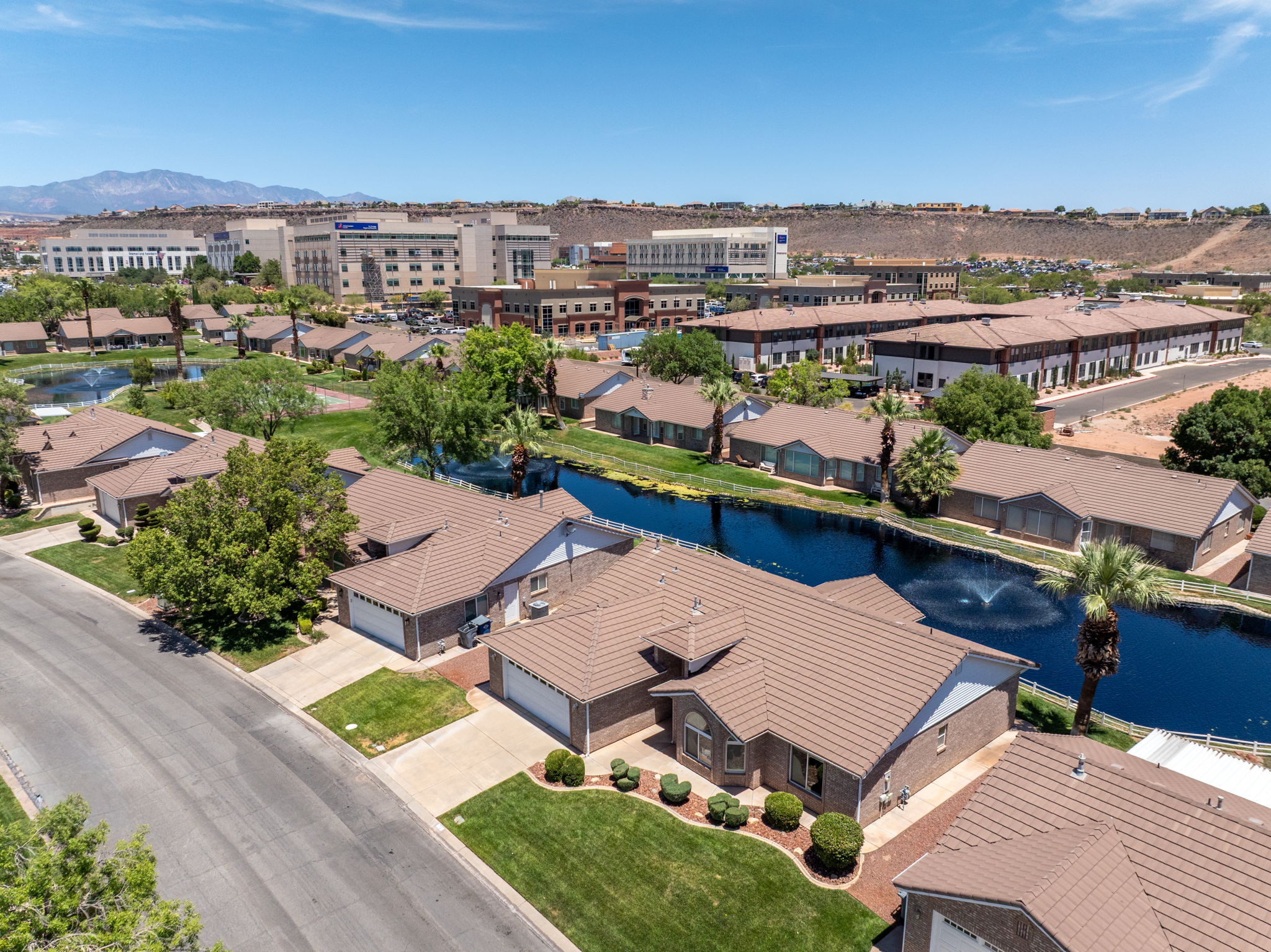Aerial perspective highlighting a residential community with an artificial waterway featuring a fountain, surrounded by single-story homes with tiled roofs