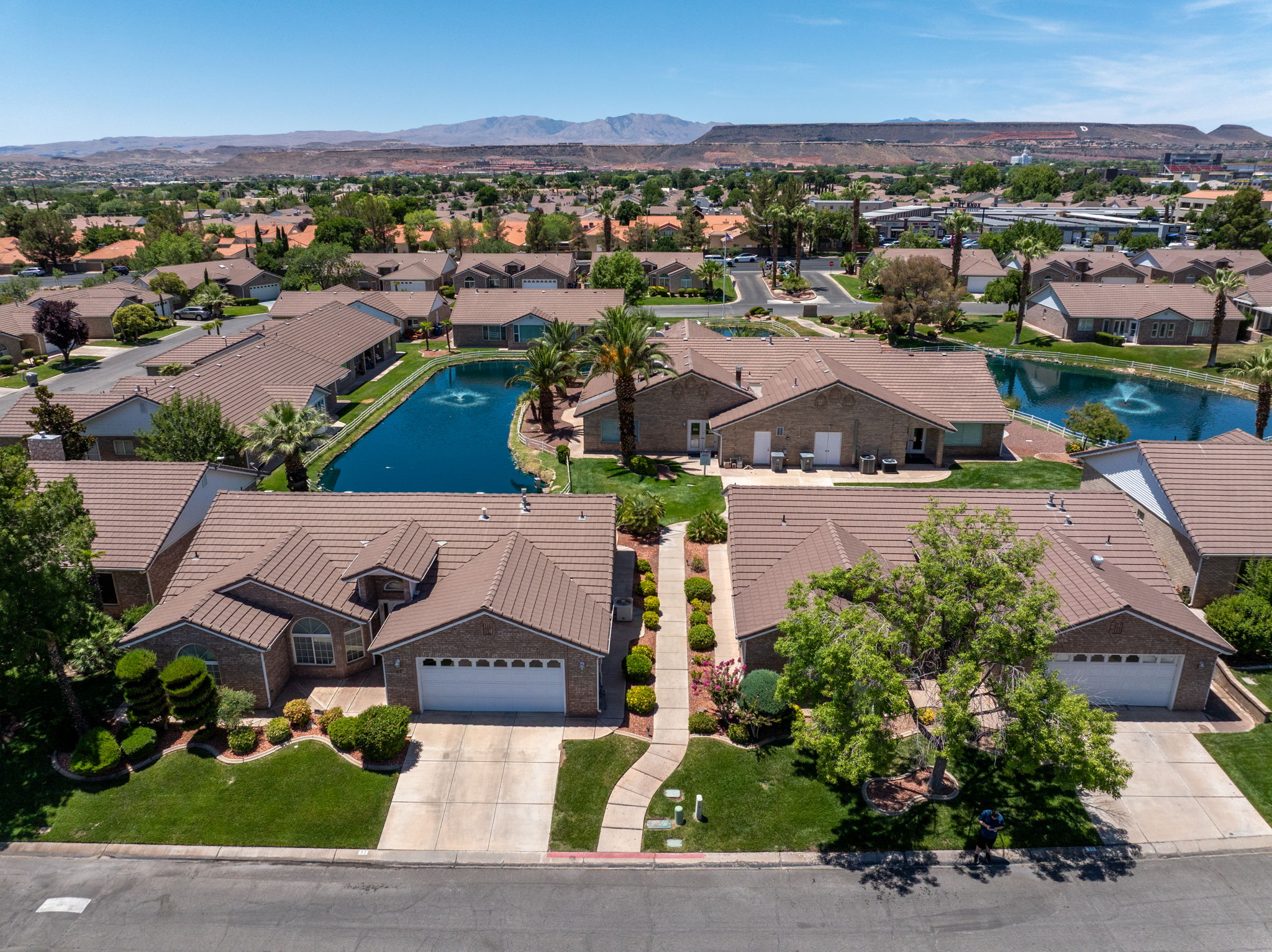 Residential community featuring manicured landscaping, mature trees, and a central water feature with fountain