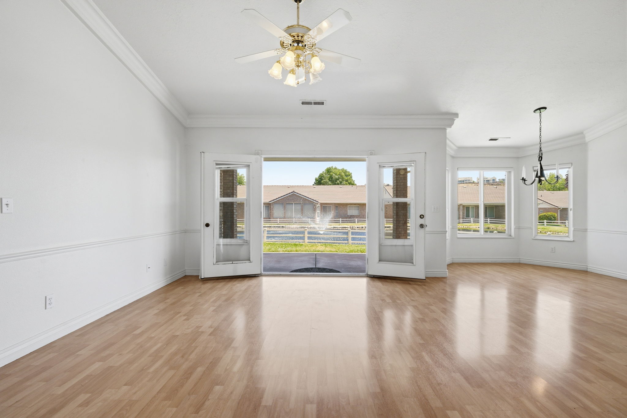 Expansive room with wood-finish flooring, crown molding, and wainscoting