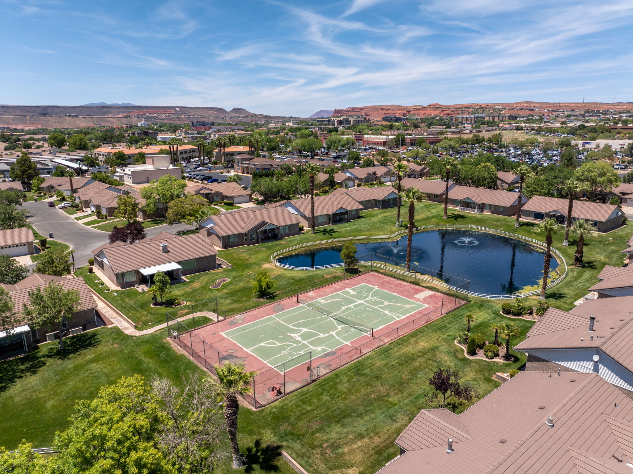 Community amenities featuring a central pond with fountains, a tennis court, and surrounding green spaces