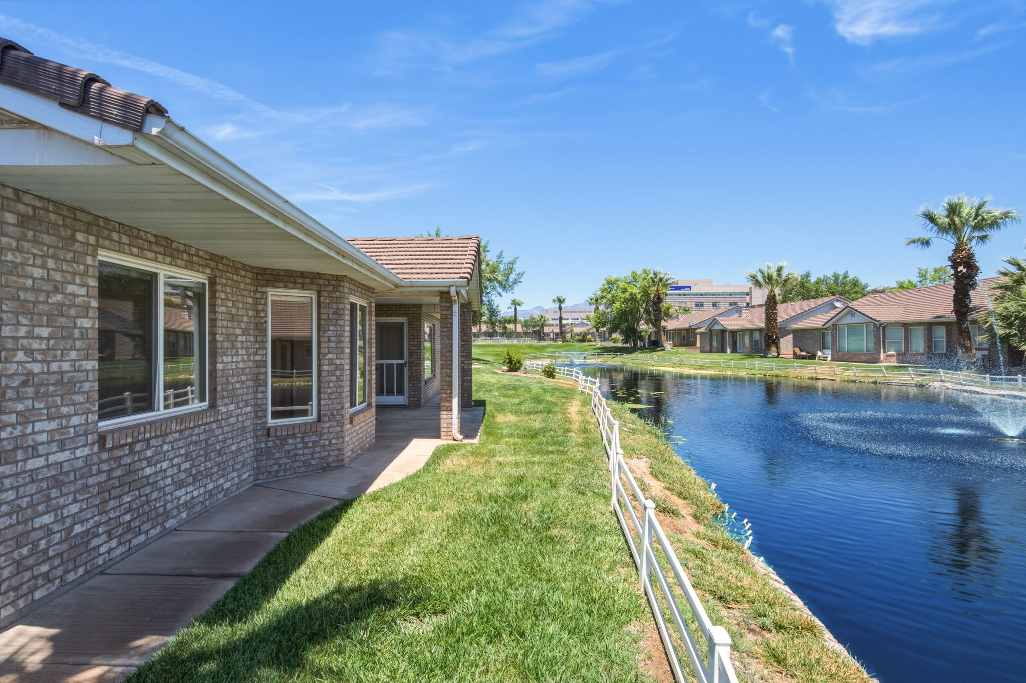 Brick exterior with a tiled roof and covered patio alongside a water feature with fountain