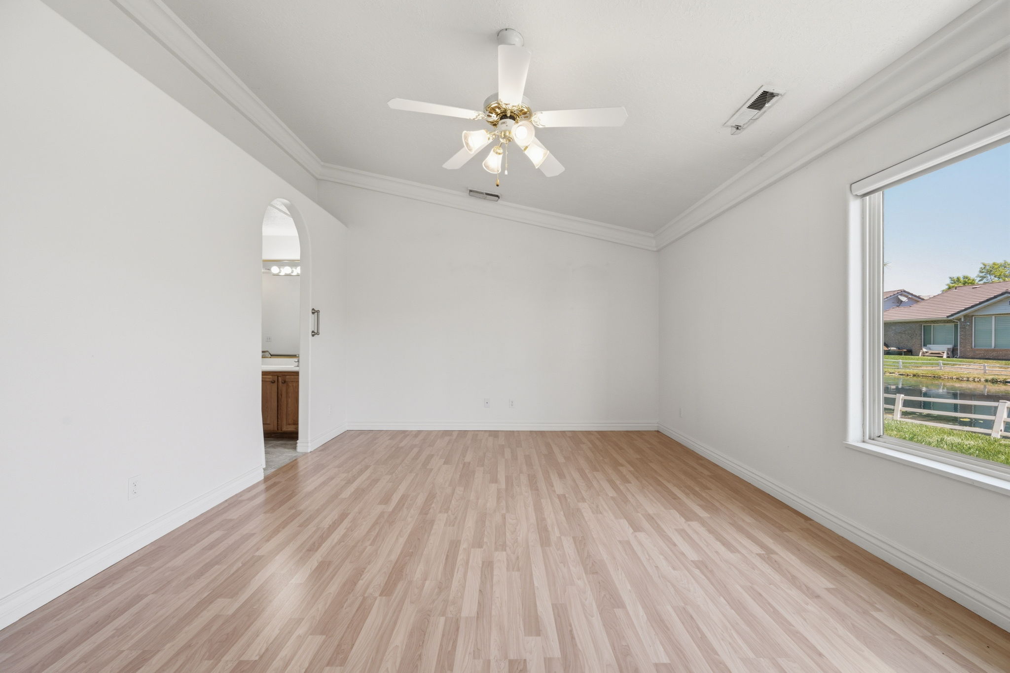 Room featuring wood-finish flooring, white walls, and crown molding