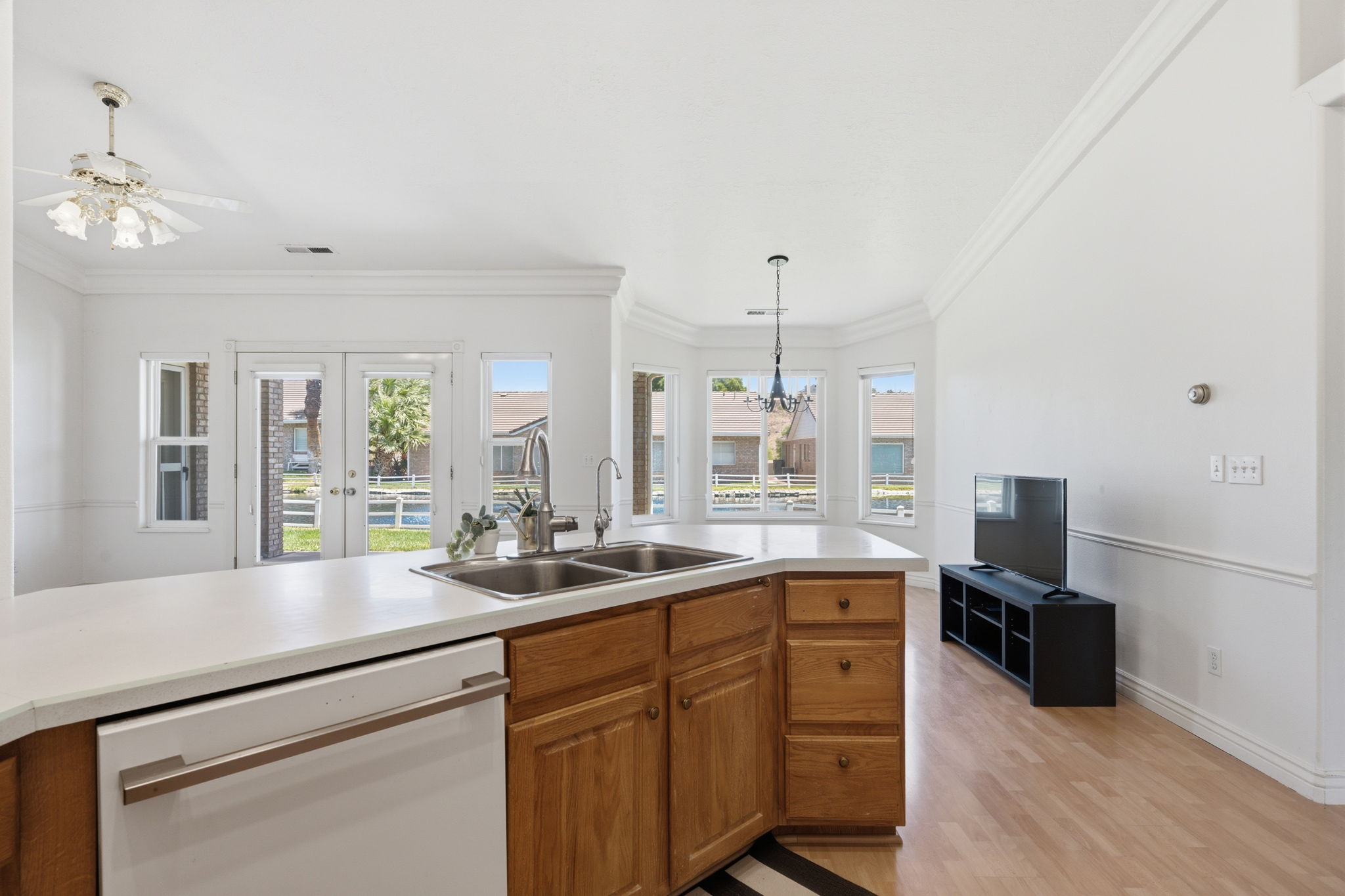 Open-concept living space featuring a kitchen island with dual sinks, wood cabinetry, and a light-colored countertop