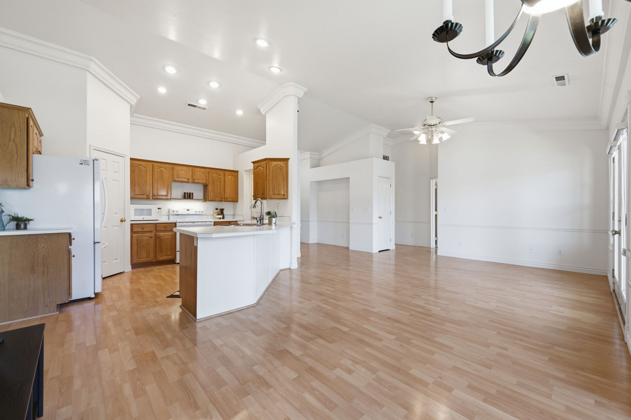 Open-concept living space featuring wood-finish flooring, vaulted ceilings with crown molding, and recessed lighting