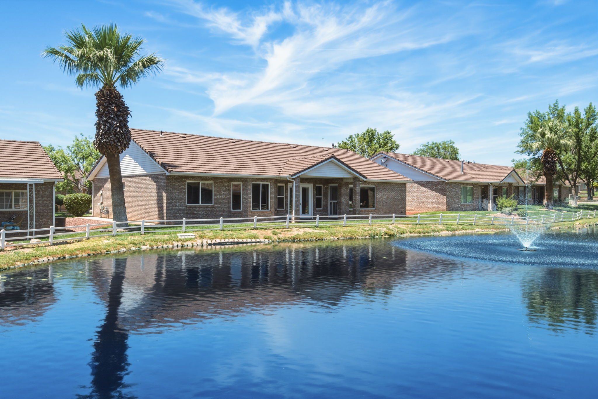 Brick exterior residential building featuring a tile roof, multiple windows, and an outdoor patio with a covered section