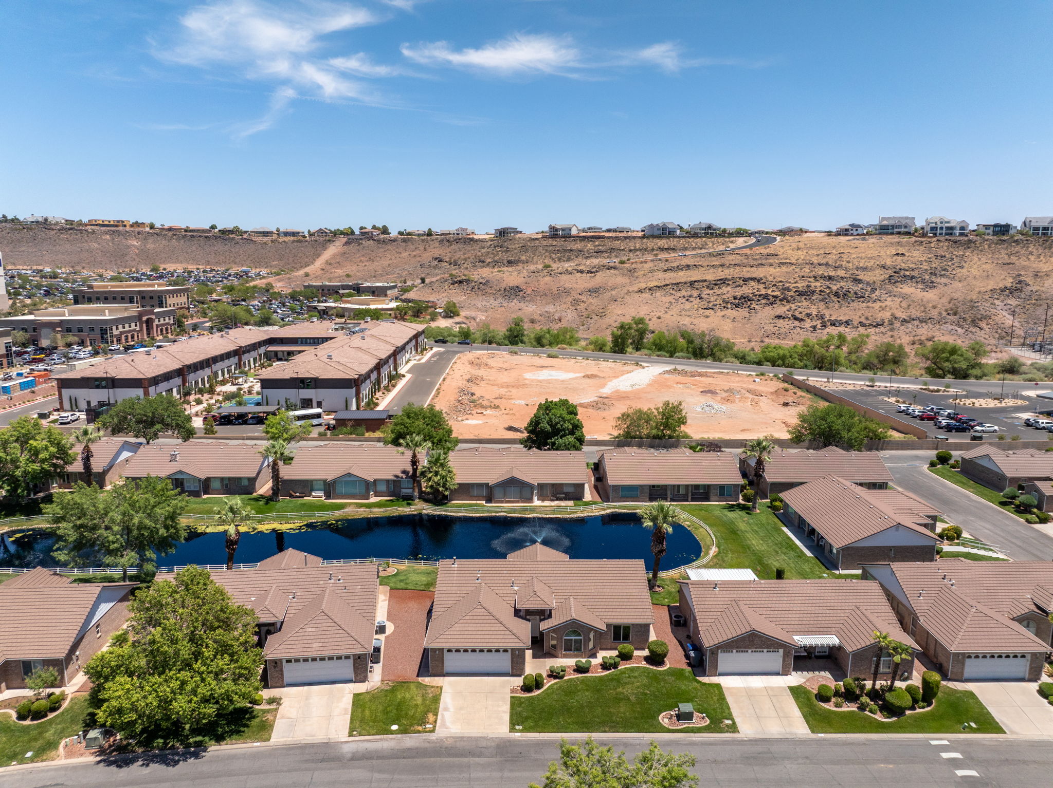 Residential community featuring a prominent water feature, single-story homes with tile roofs, and manicured landscaping