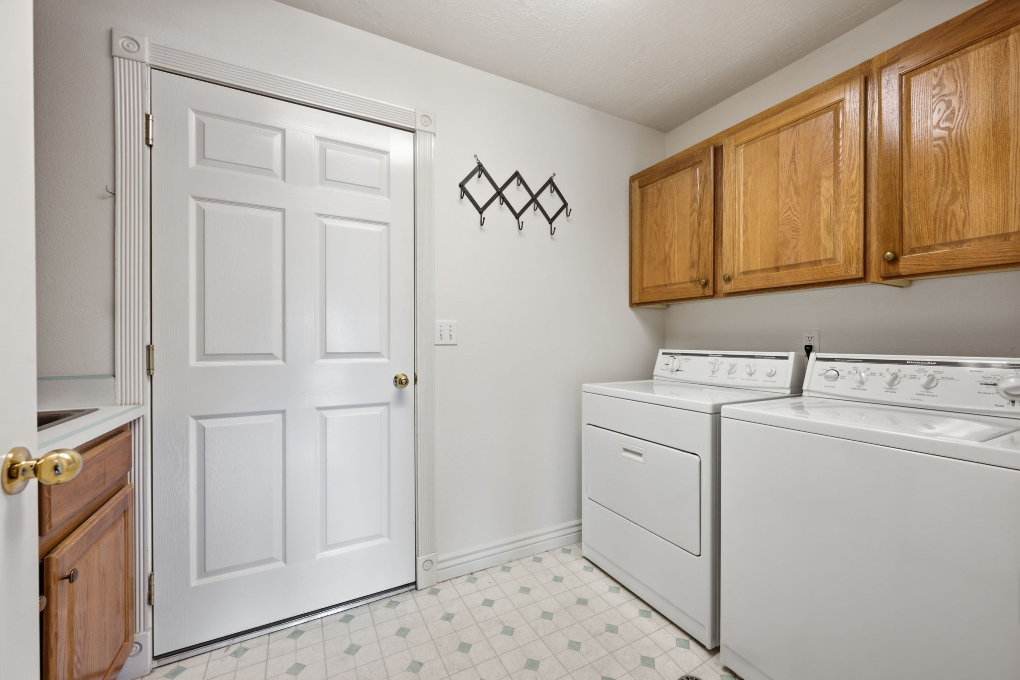 Dedicated laundry space featuring a white paneled door, wood-finish cabinetry, and pattern flooring