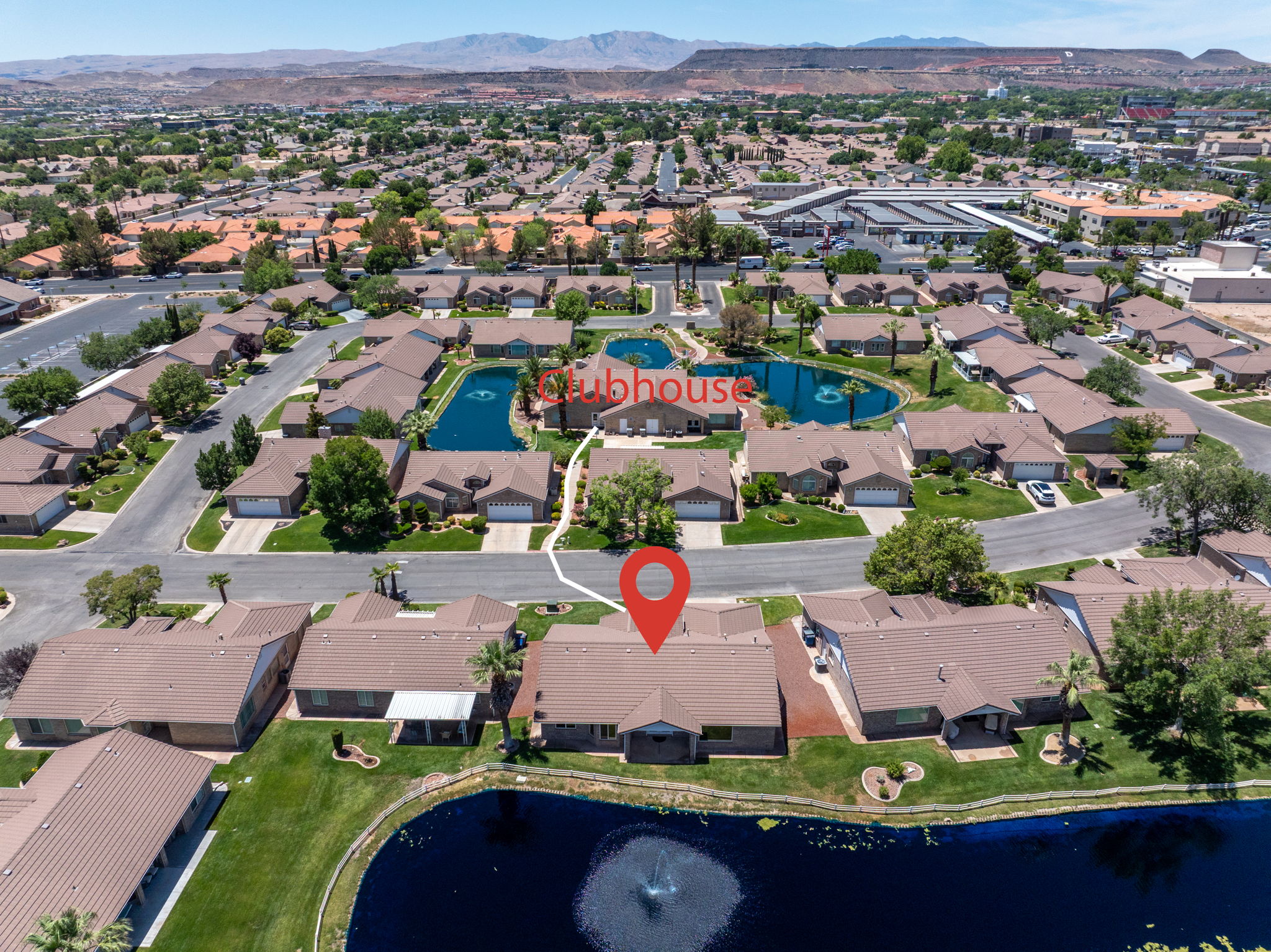 Community setting featuring a central pond with fountains, mature landscaping, and single-story residences with attached garages