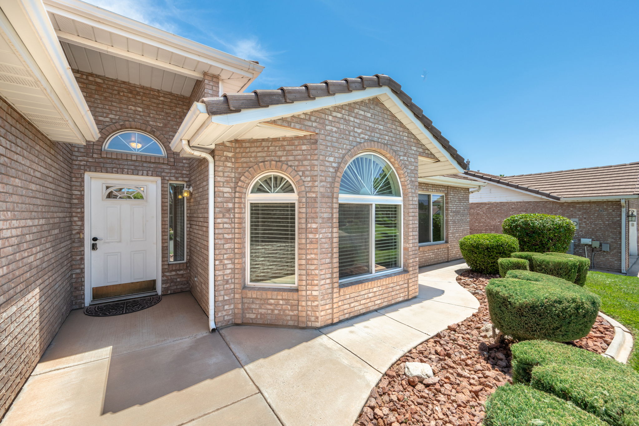 Brick exterior with a white entry door, arched transom window, and an arched window with blinds