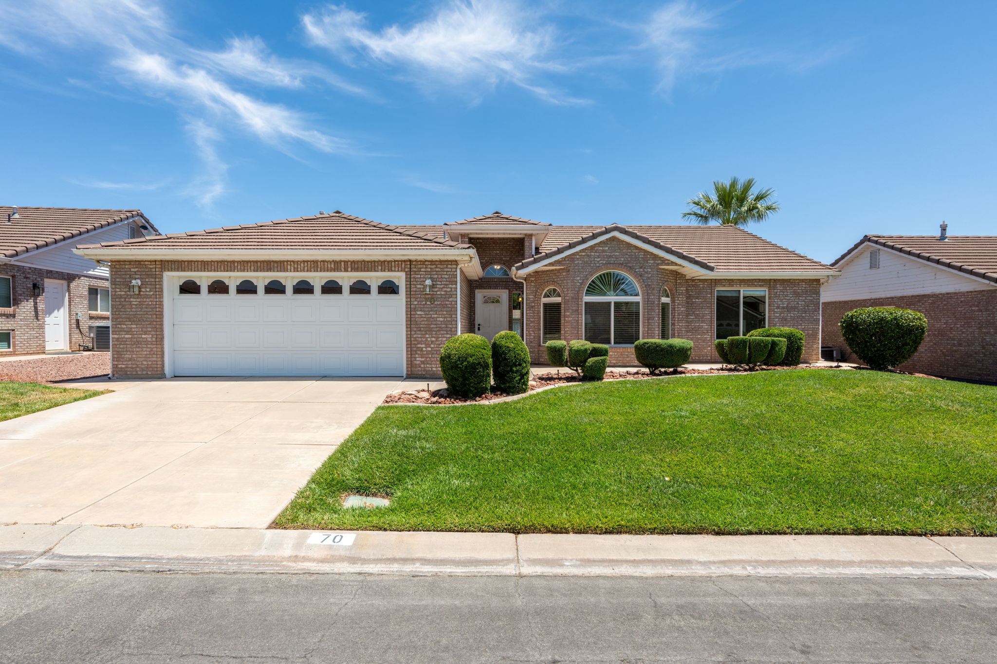 Brick exterior home featuring a two-car garage with arched window inserts