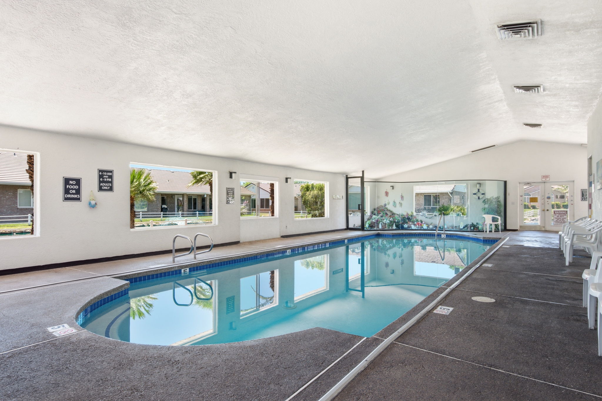 Indoor swimming pool featuring a curved entry, blue tile trim, and multiple large windows