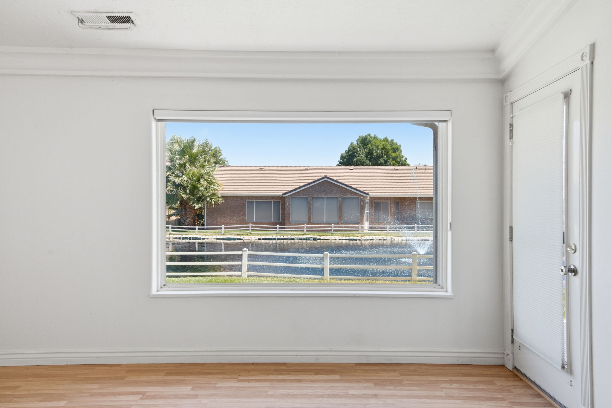 Interior space featuring a large window, wood-finish flooring, white walls, and crown molding