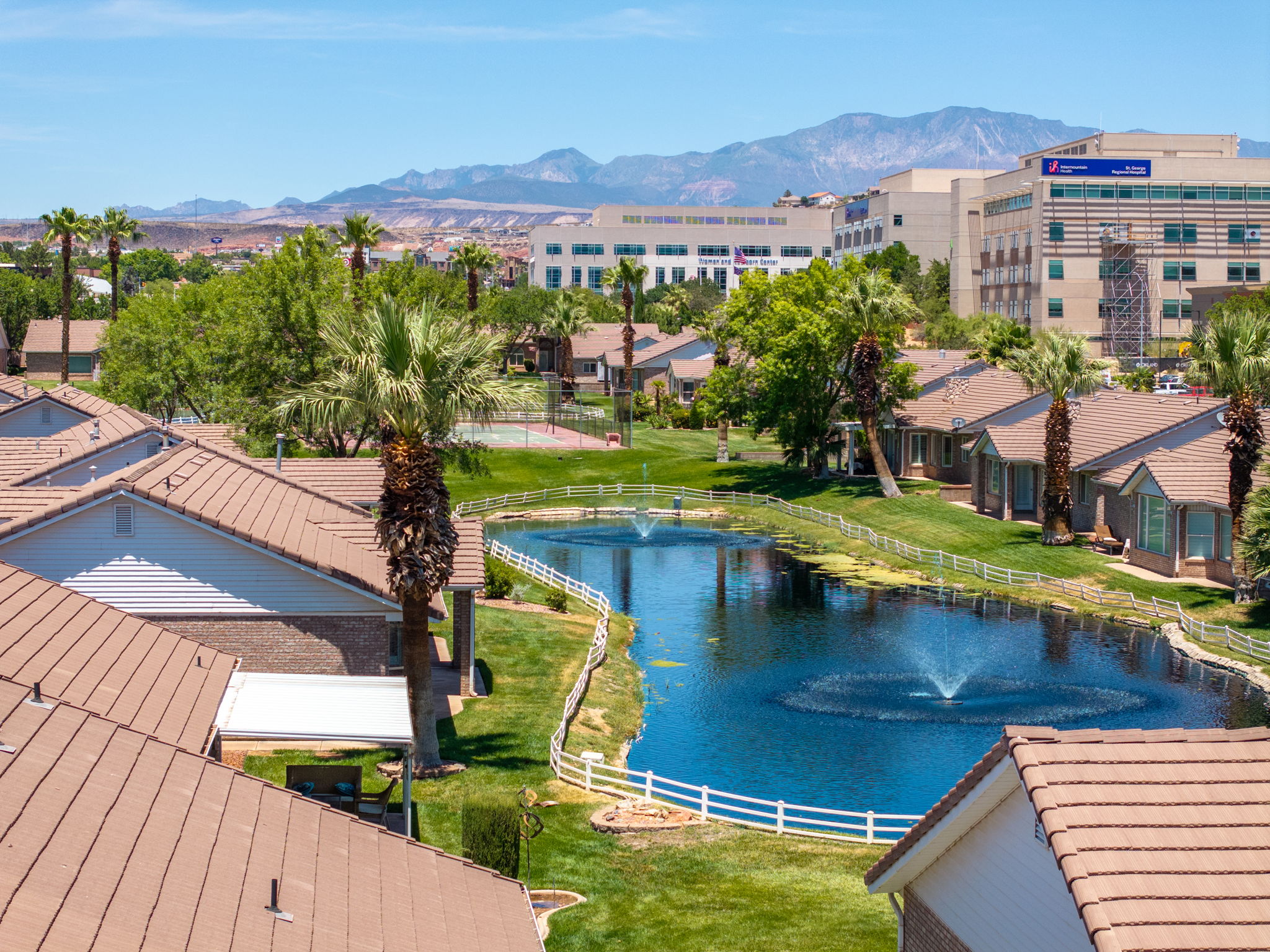 Community pond with dual water features, surrounded by manicured green spaces and palm trees