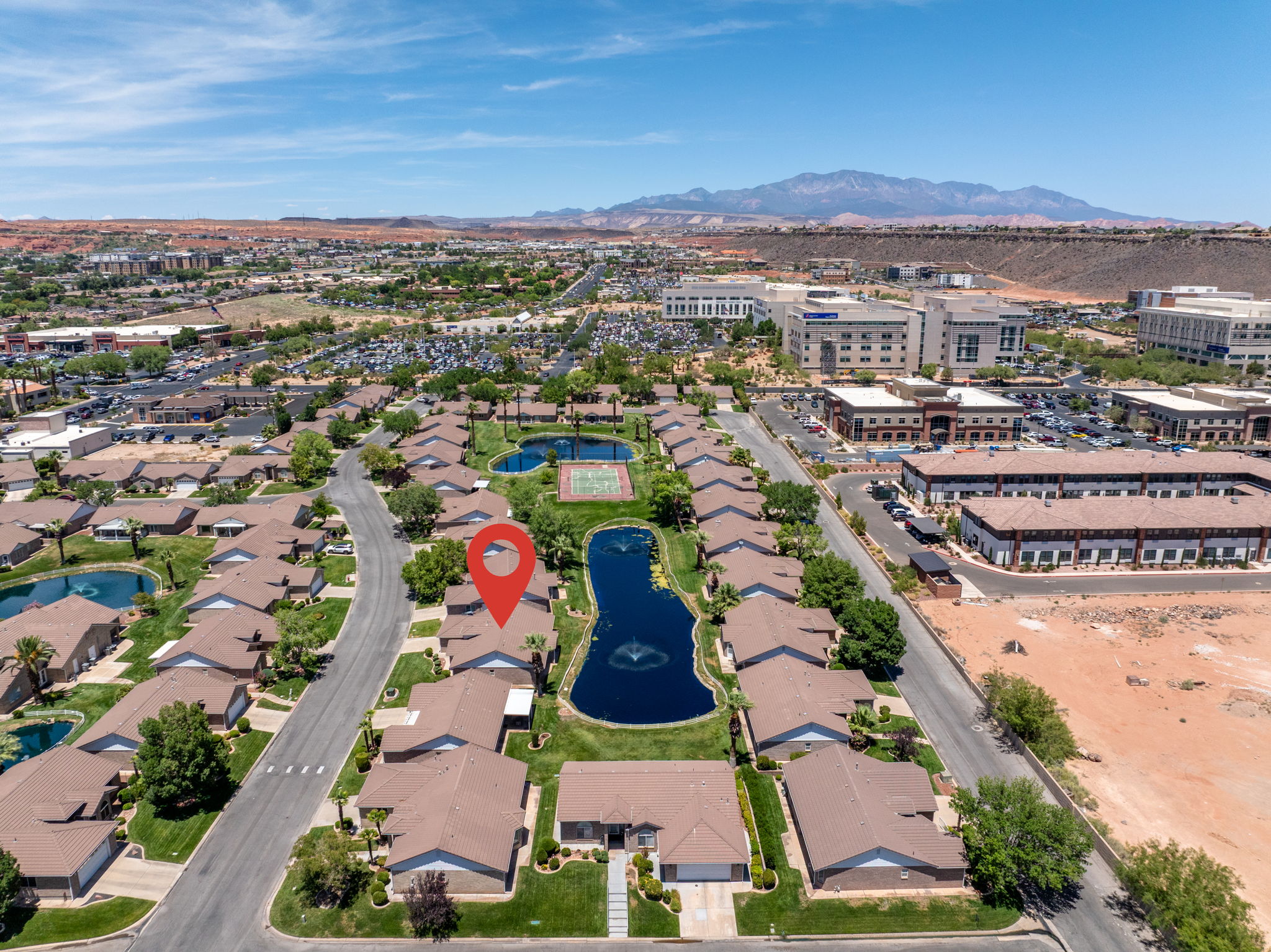 Aerial view showcasing the property within a community featuring multiple ponds with fountains