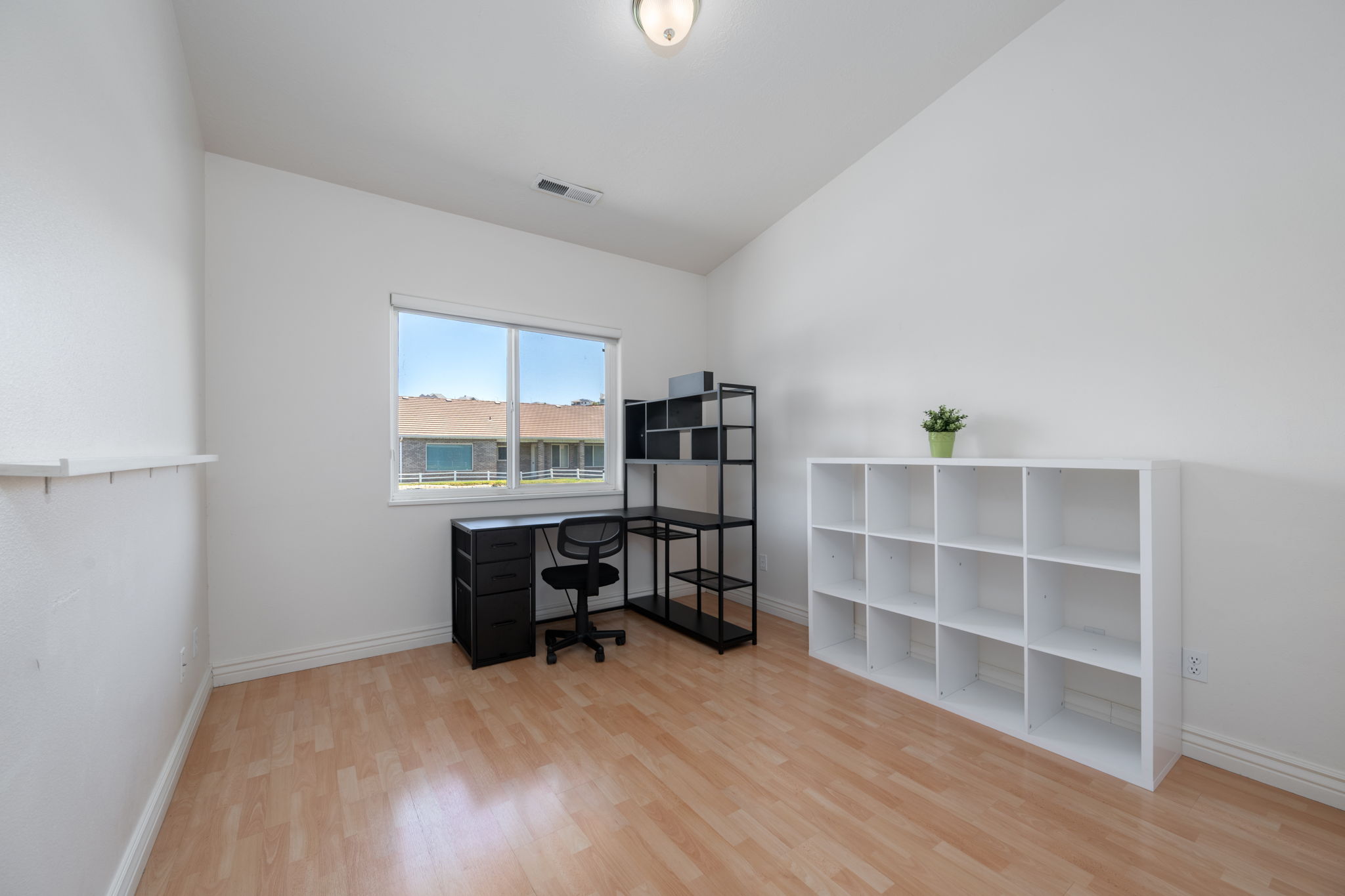 Bright room featuring wood-finish flooring, white walls, and a large window