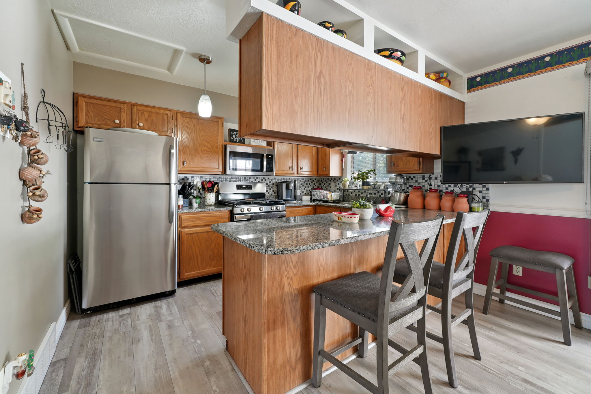 Kitchen featuring wood-finish cabinetry, granite countertops, and a mosaic tile backsplash