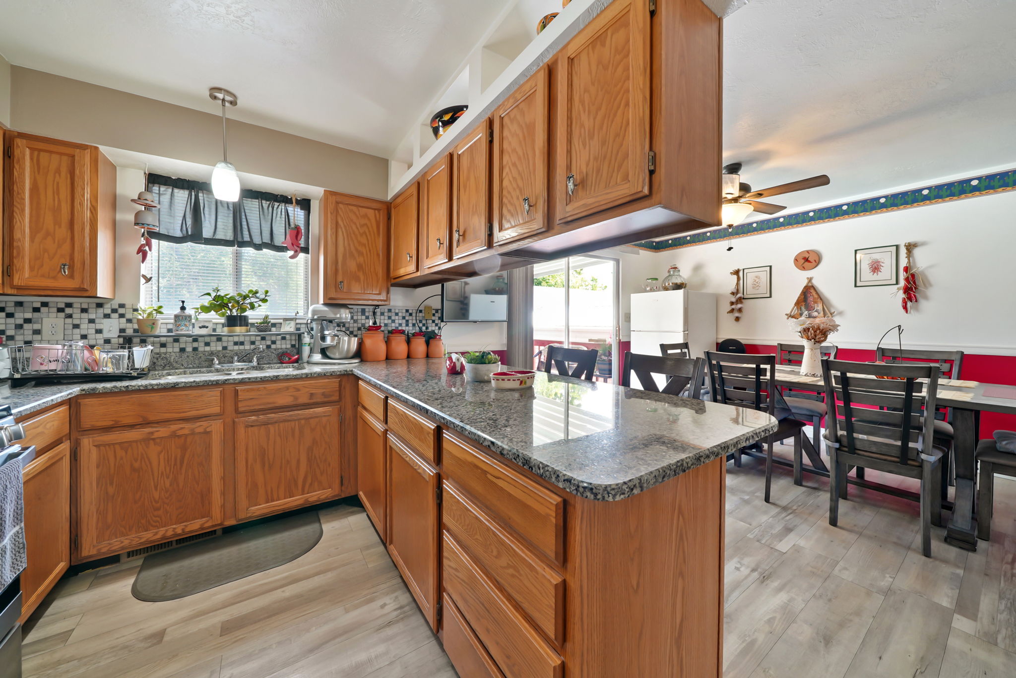 Kitchen featuring wood cabinetry, granite countertops, tile backsplash, and a stainless steel sink with a window overhead