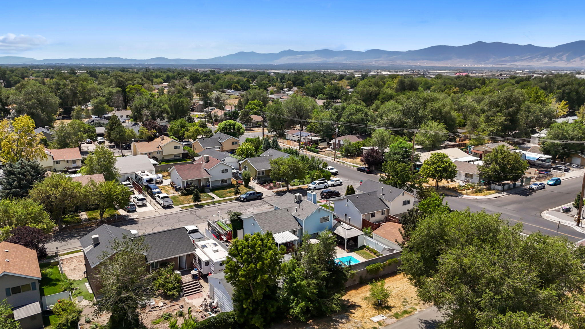 Aerial perspective showcasing a residential area with mature trees and a distant mountain range