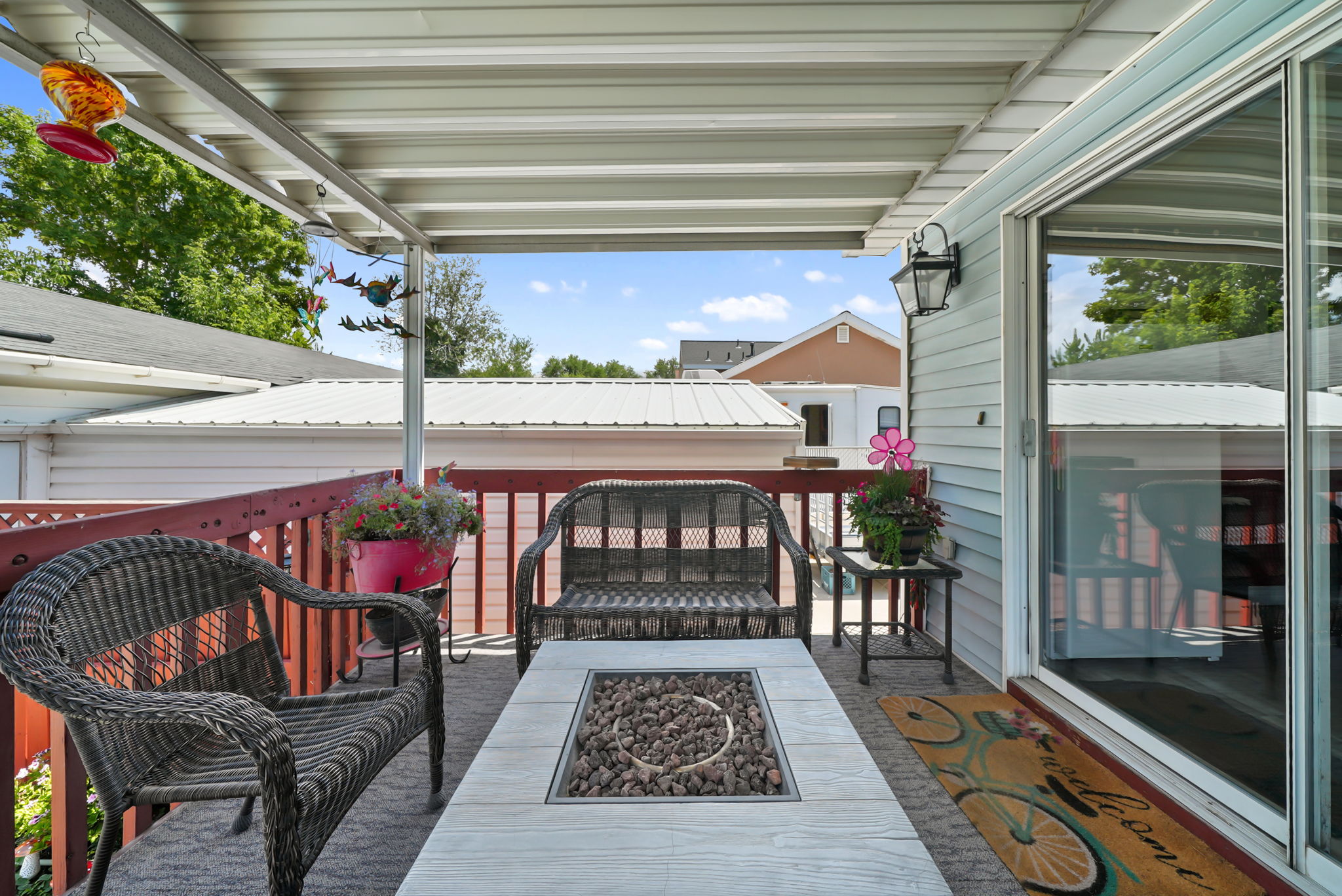 Covered outdoor patio featuring a fire pit table, light blue siding, and a sliding glass door