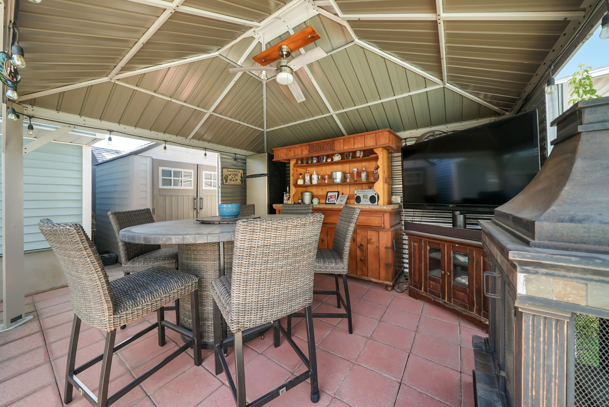 Covered patio area featuring a metal gazebo, ceiling fan, and tiled flooring
