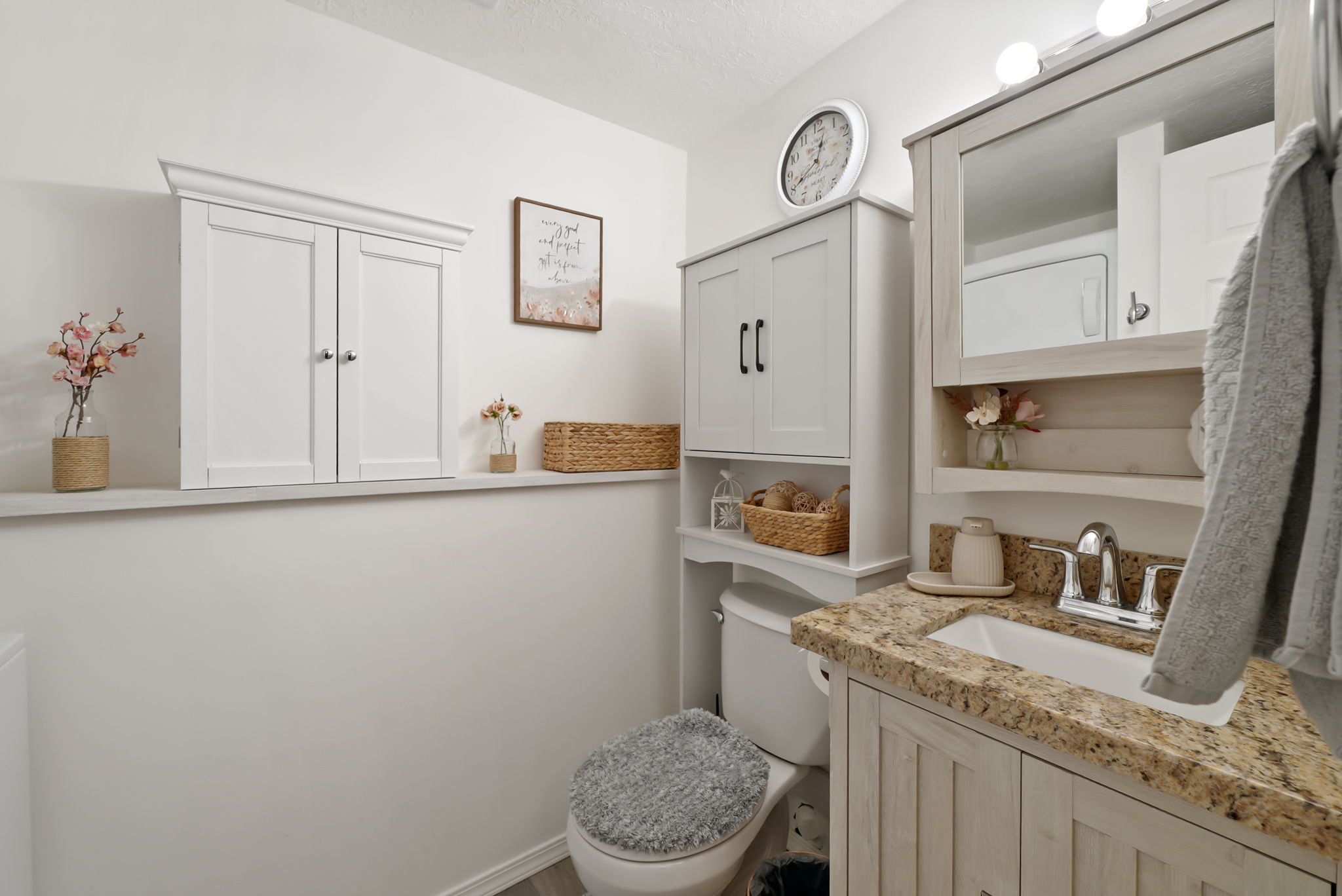 Bathroom vanity featuring a light wood-finish cabinet with a granite countertop, undermount sink, and chrome faucet