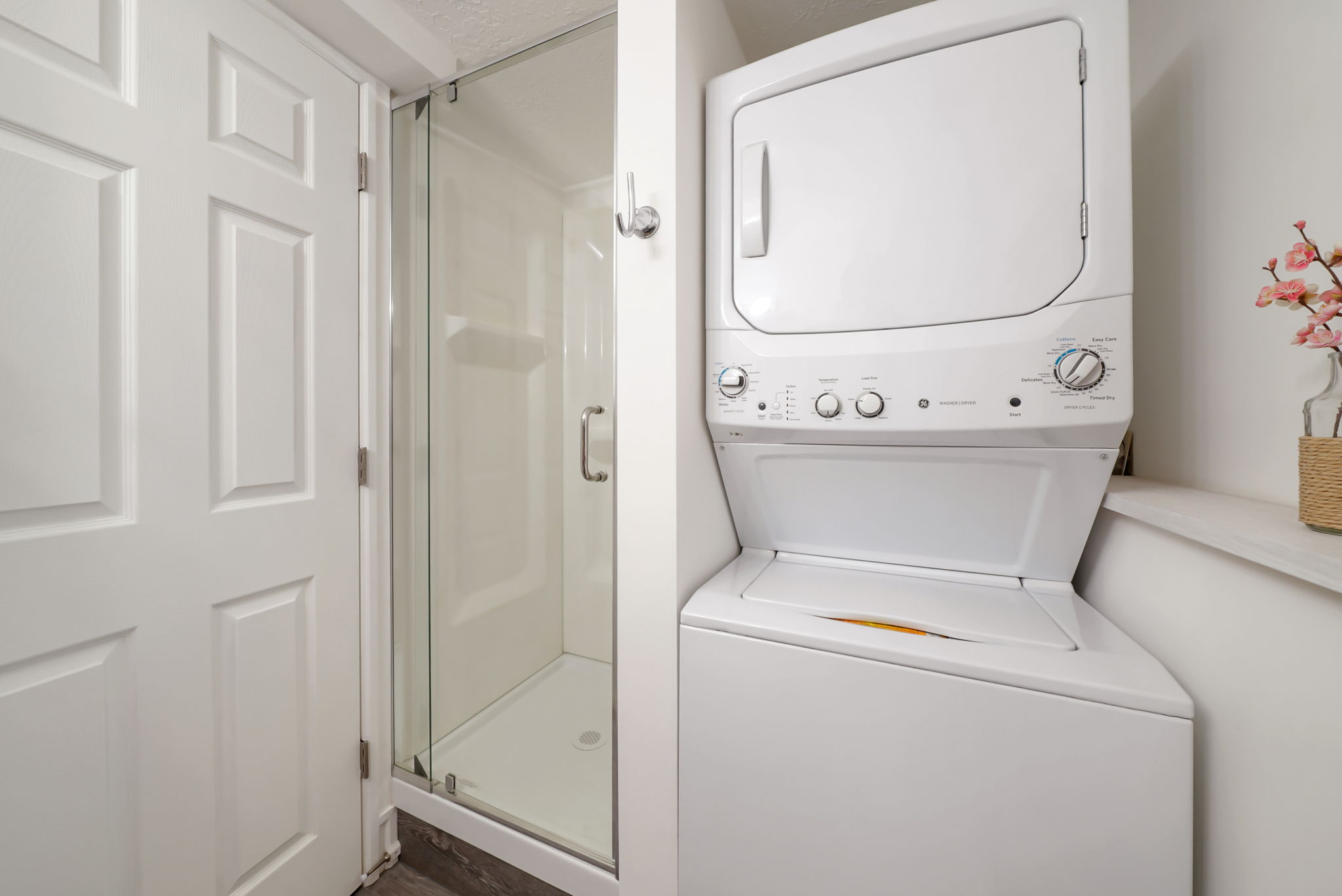 Compact laundry area featuring a stacked washer and dryer unit