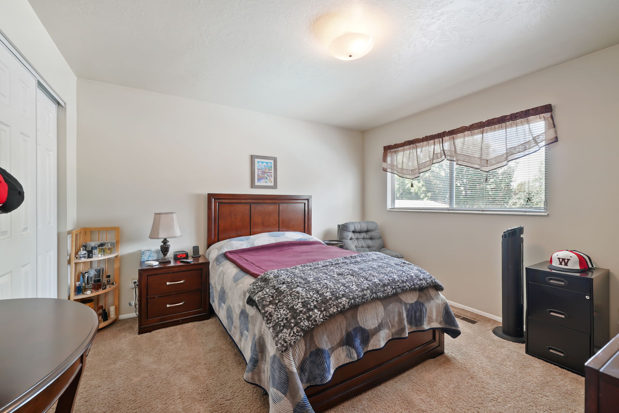 Bedroom featuring neutral wall paint, carpet flooring, a window with venetian blinds, and a bi-fold closet door