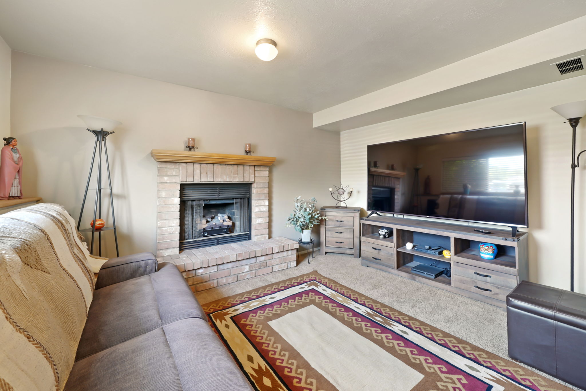 Brick-surround fireplace with a wood mantle and hearth, recessed ceiling lighting, and carpet flooring
