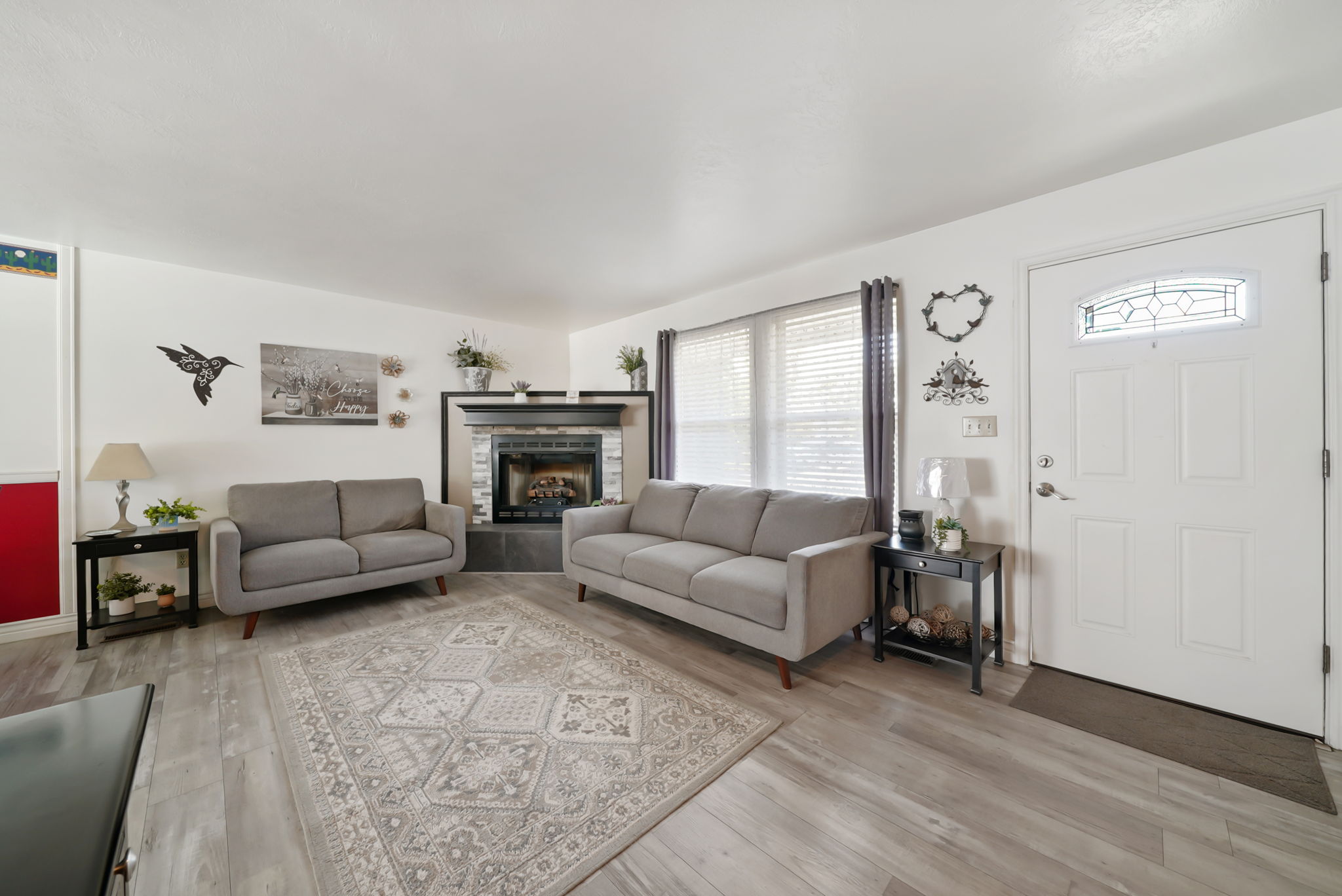 Living area featuring wood-finish flooring and a corner fireplace with a stone surround