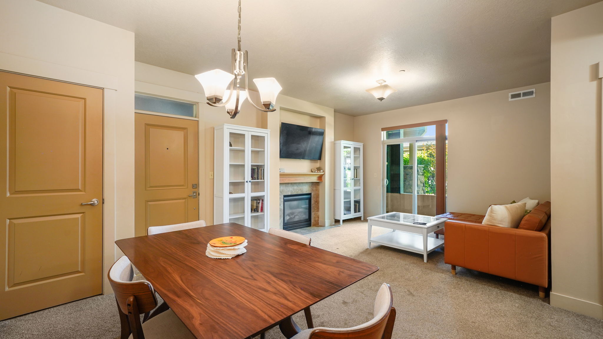 Open concept living and dining area featuring a built-in fireplace, recessed lighting, a ceiling-mounted light fixture, and a glass-paneled exterior door