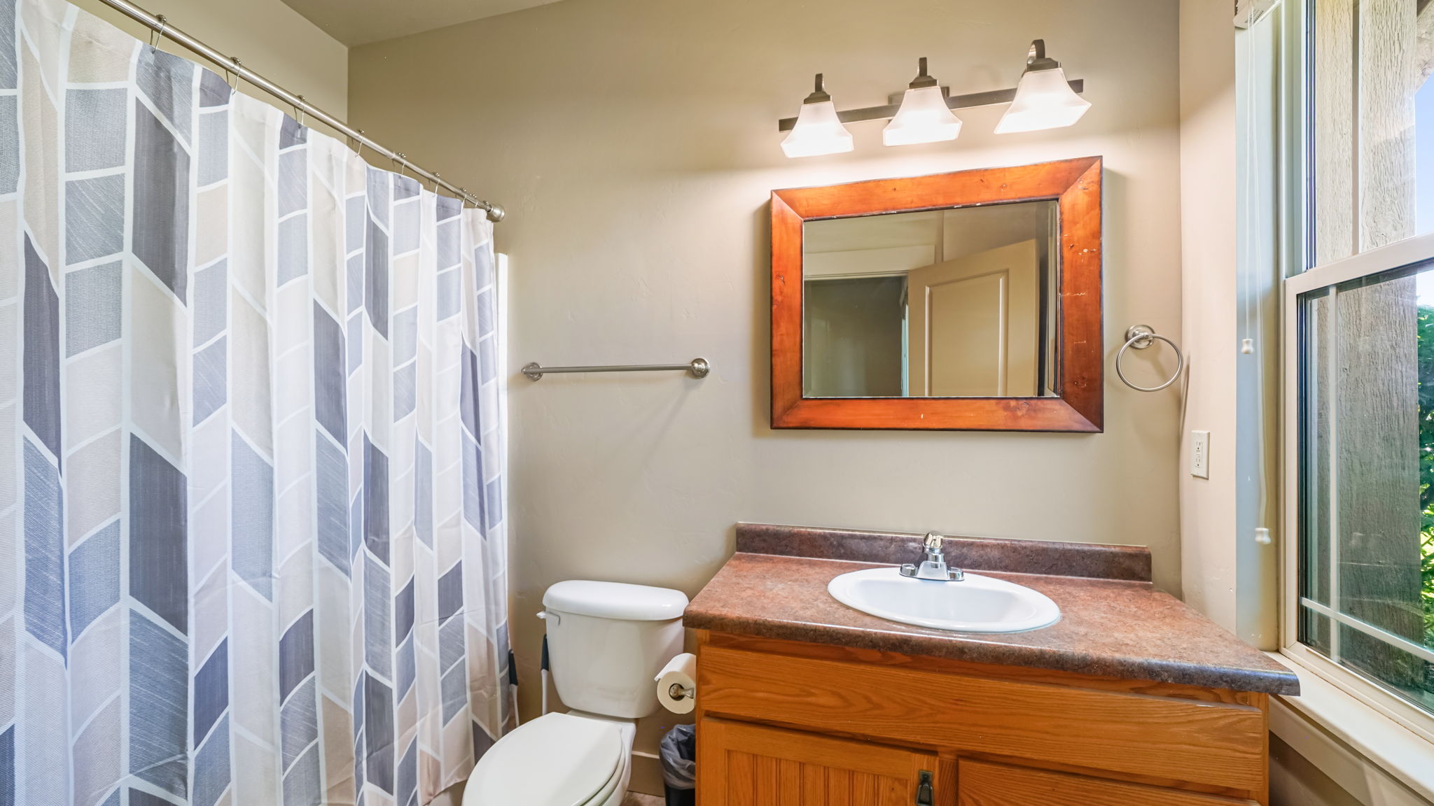 Bathroom featuring a vanity with a wood-finish cabinet, integrated sink, and an overhead light fixture