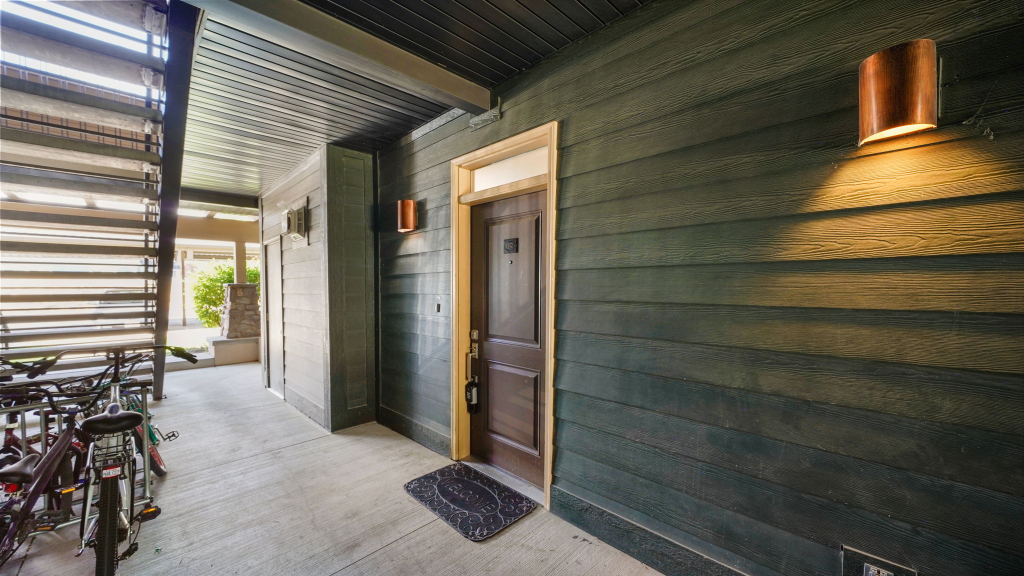 Covered entry featuring plank siding and a dark wood-finish door with white trim