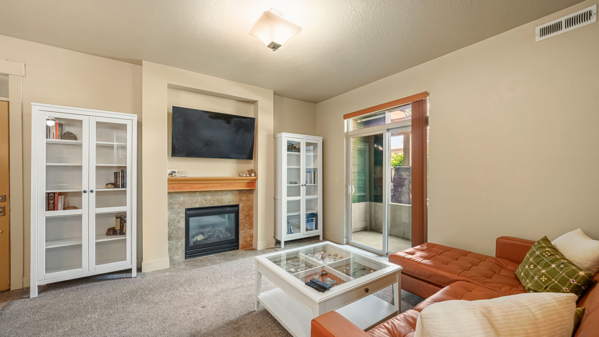 Living area featuring a gas fireplace with a wood mantle and stone surround, built-in recessed television alcove, and light-colored wall-to-wall carpeting