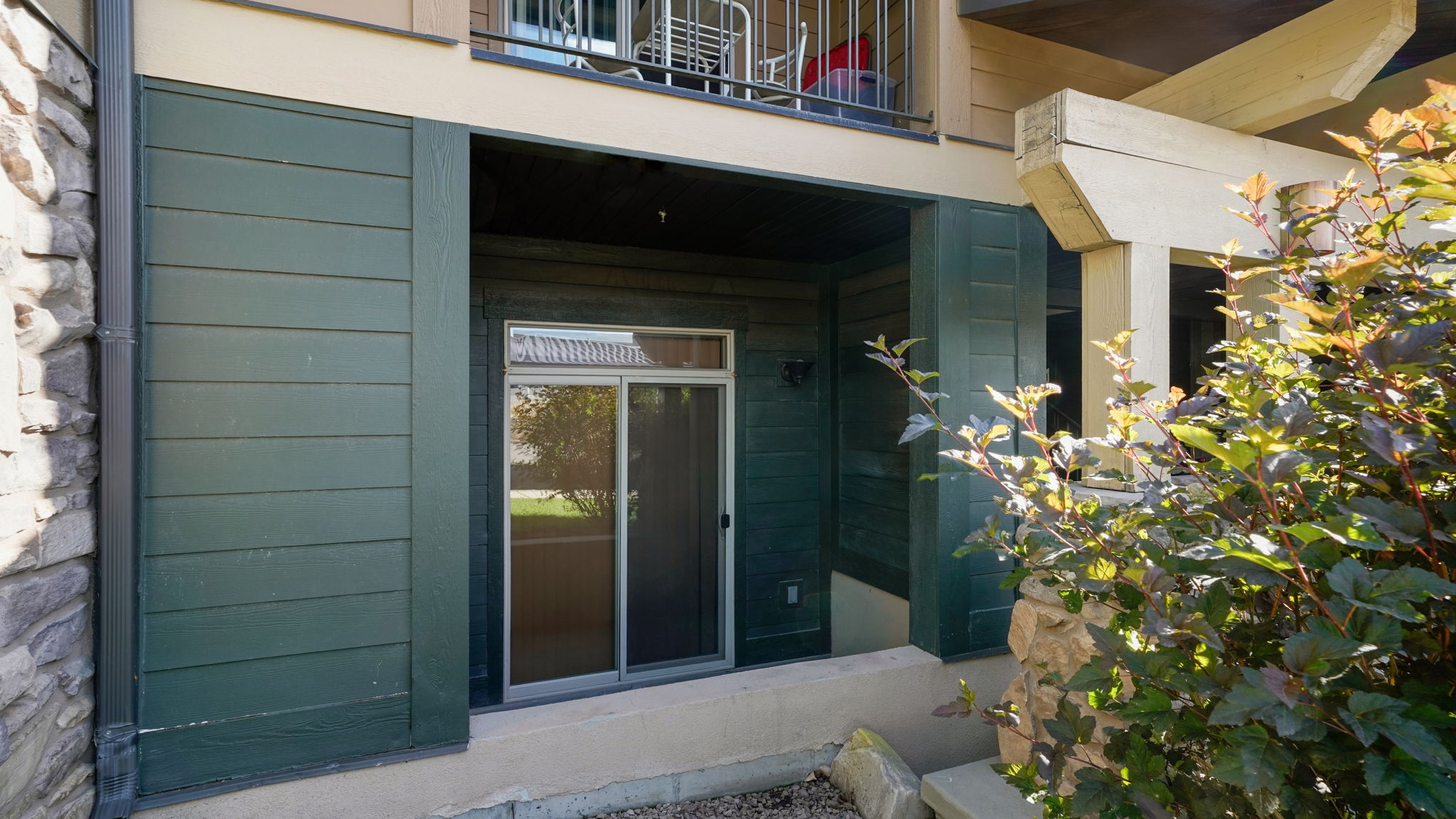 Ground-level patio featuring sliding glass doors and dark green siding
