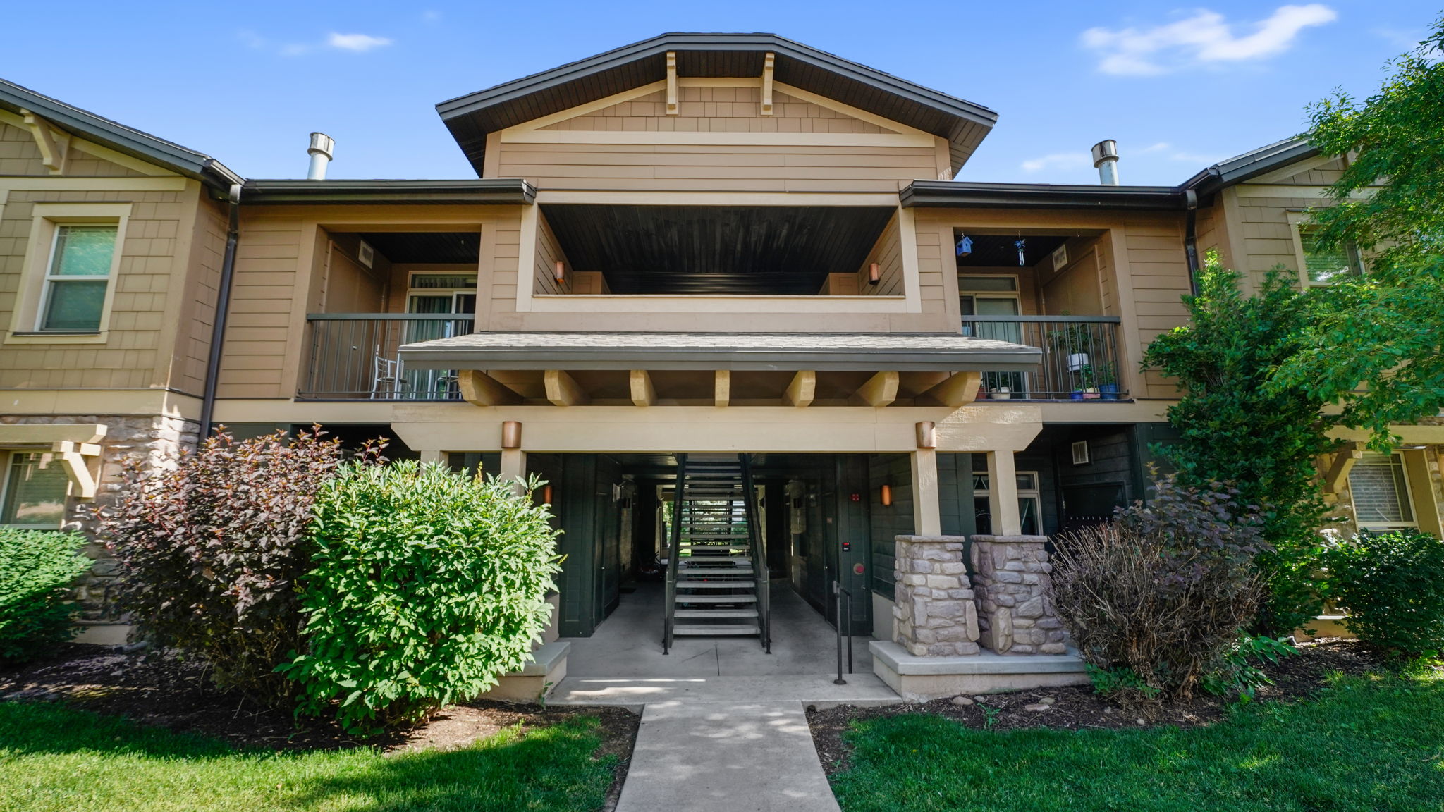 Multi-level residential building featuring stone accents, wood siding, and covered balconies